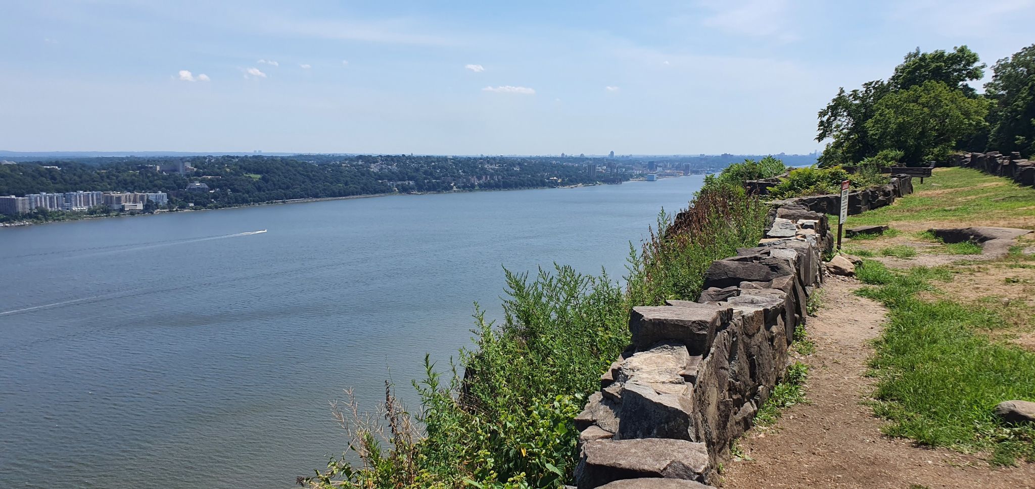 Sunny view of a wide river, distant town, and a stone-lined path. - Peanut Leap Cascade via Long Path
