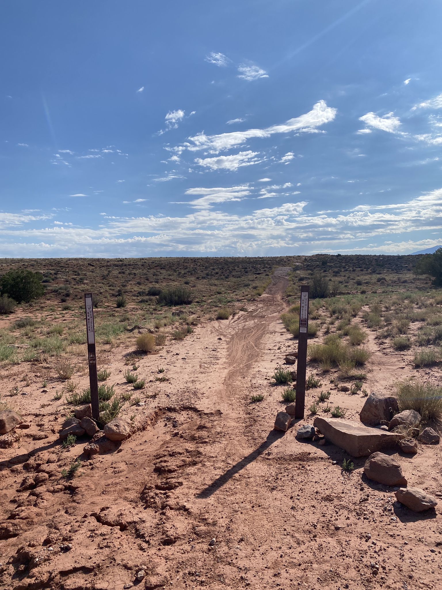 A desert trail entrance with two posts under a bright blue sky. - Bar M Loop Trail