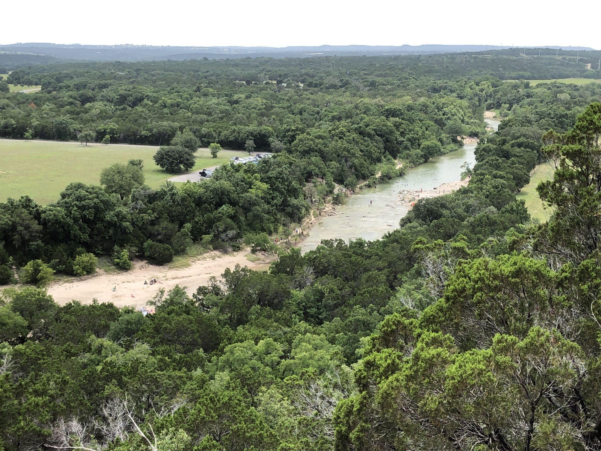 An expansive view of a winding river flowing through a dense green forest. - Cedar Brake Outer and Overlook Trail Loop