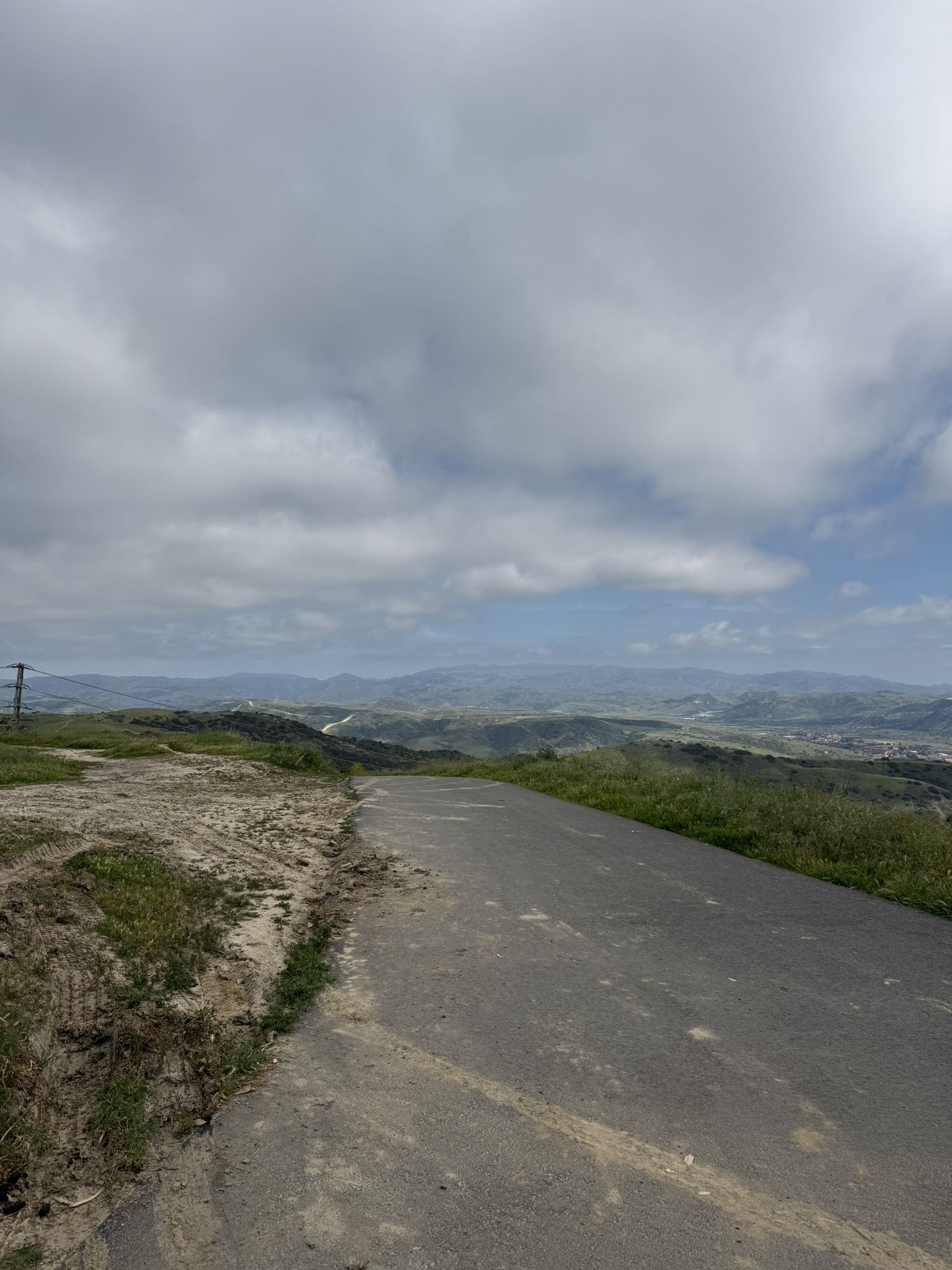 Paved path curving through green rolling hills under a cloudy sky. - San Clemente – Mountains' Lookout loop from San Clemente
