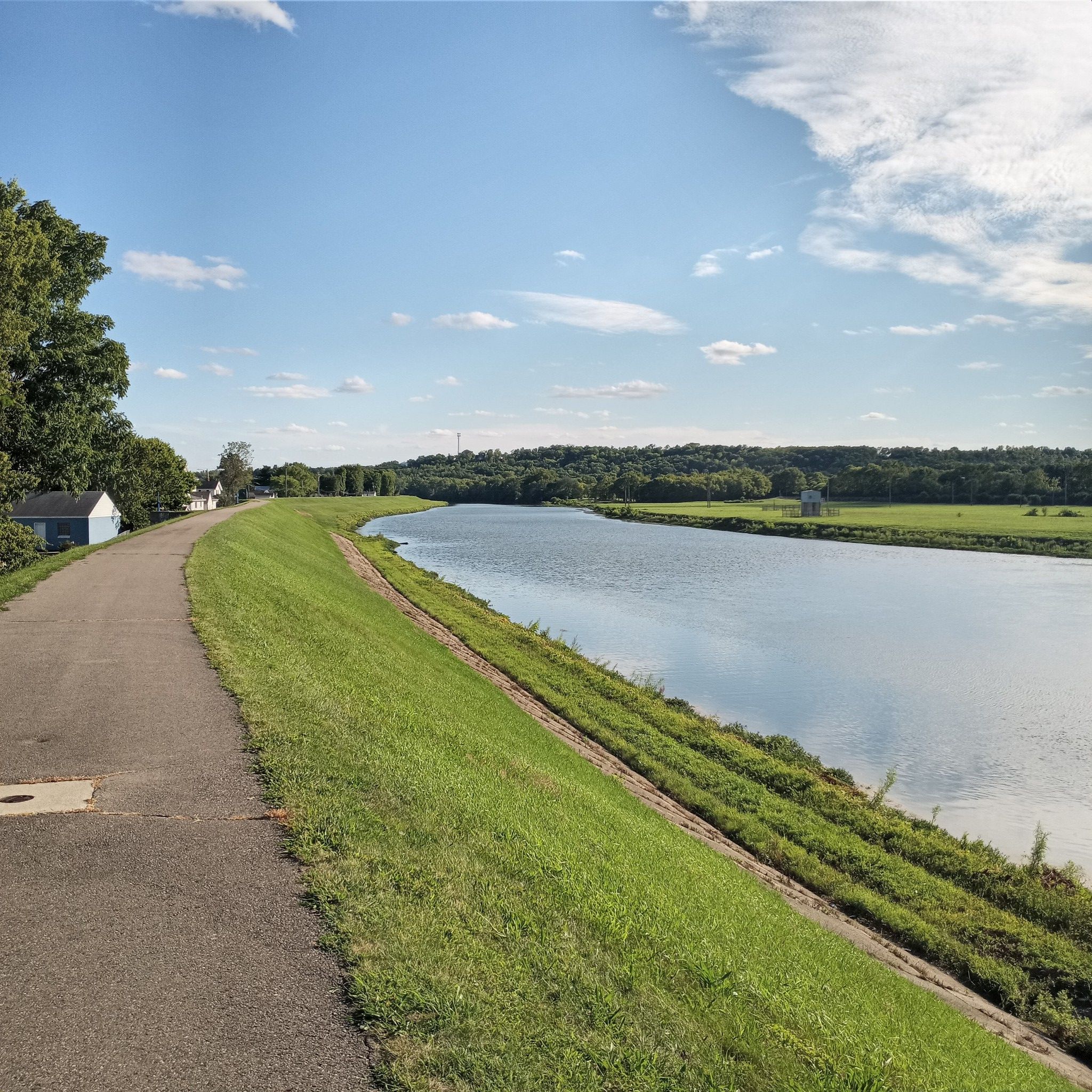 Paved path alongside a wide river with grassy banks under a sunny sky. - Hutchins State Reservoir – Miamisburg Riverfront Park loop from Miami University Middletown