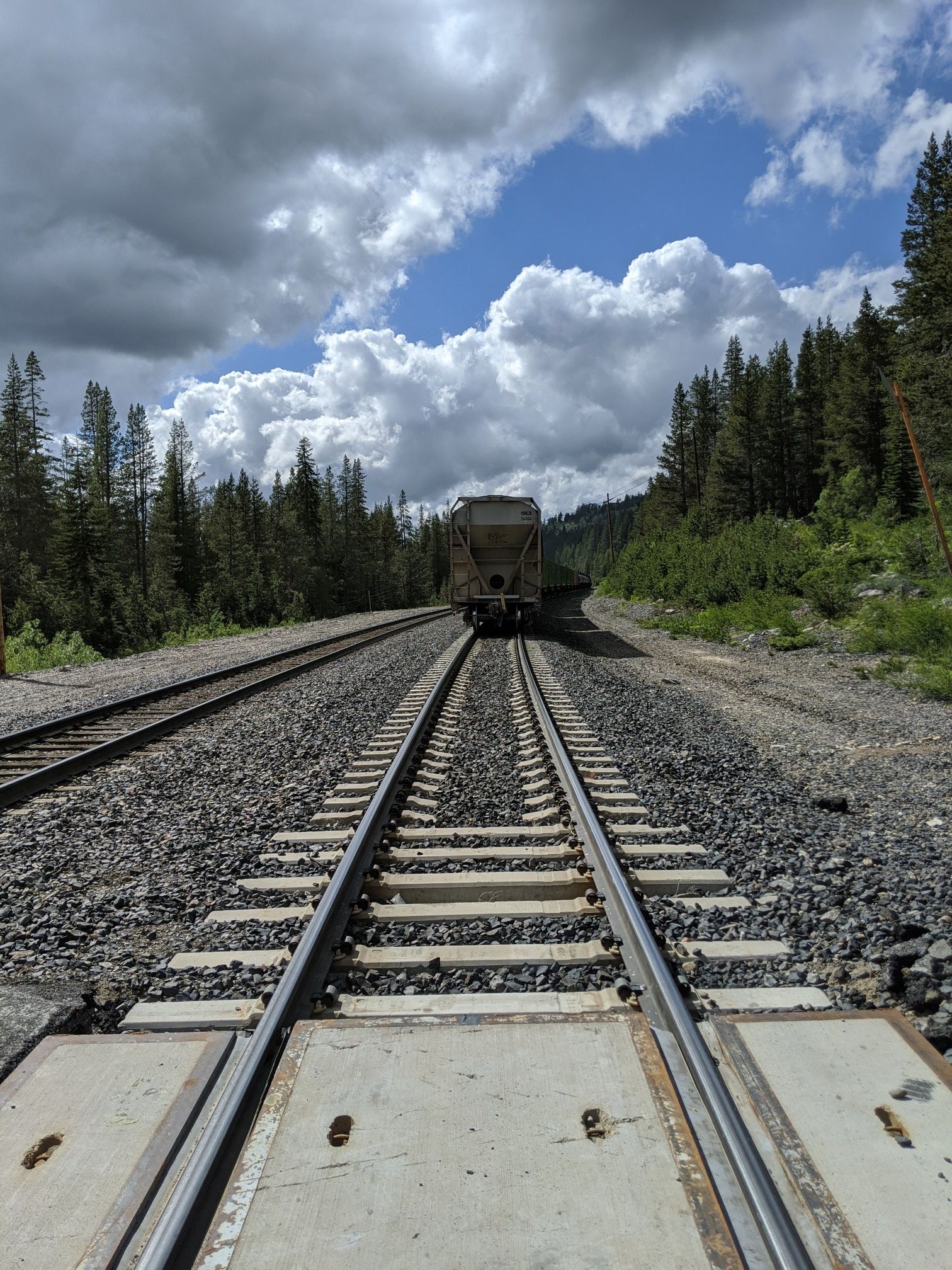 Train tracks leading to a distant train car under a partly cloudy sky. - Royal Gorge and Hewlett Rim Trail Loop