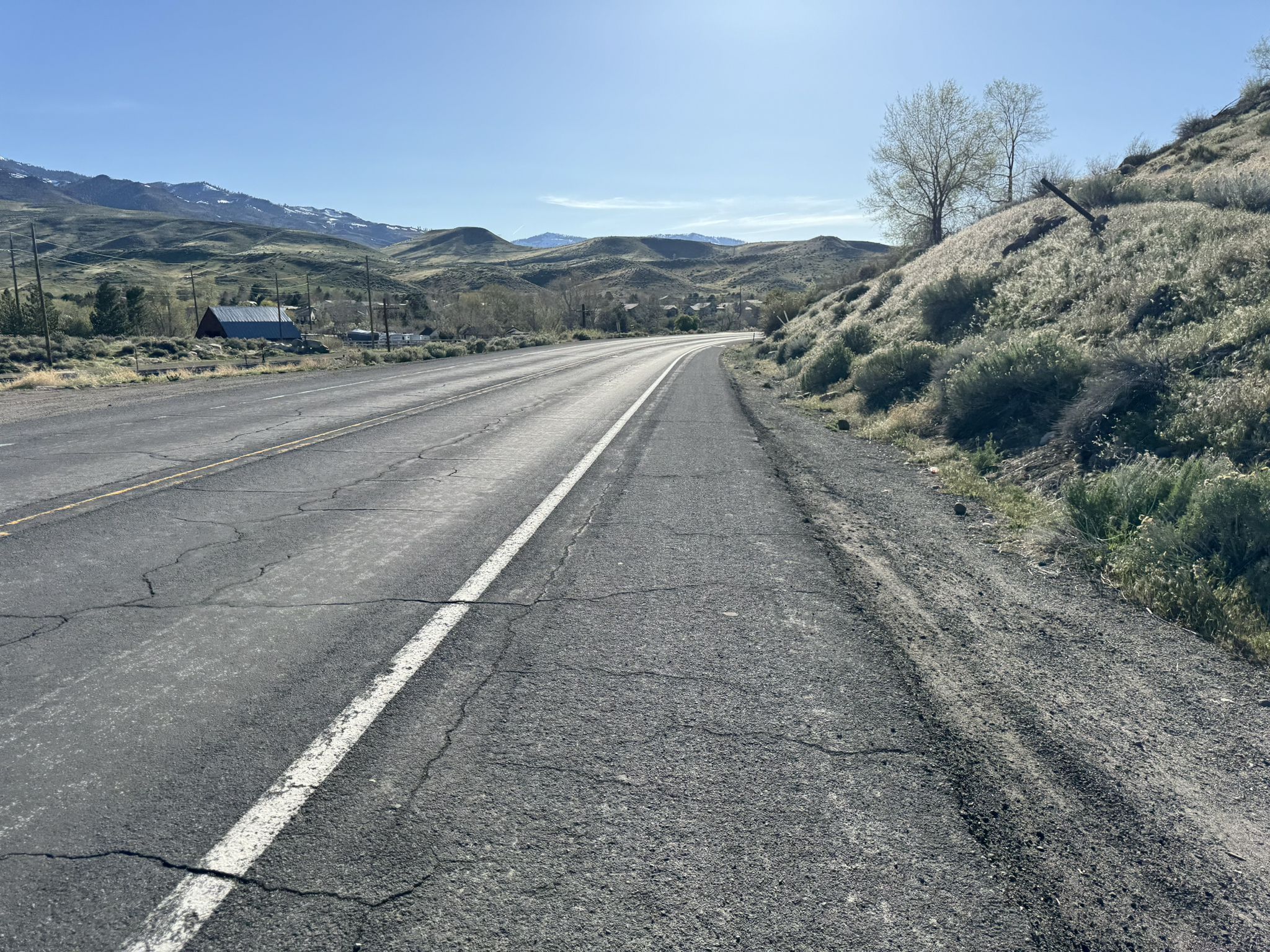 Empty paved road curving through dry, rolling hills under a clear sky. - Bartley Ranch to Crystal Peak Park loop