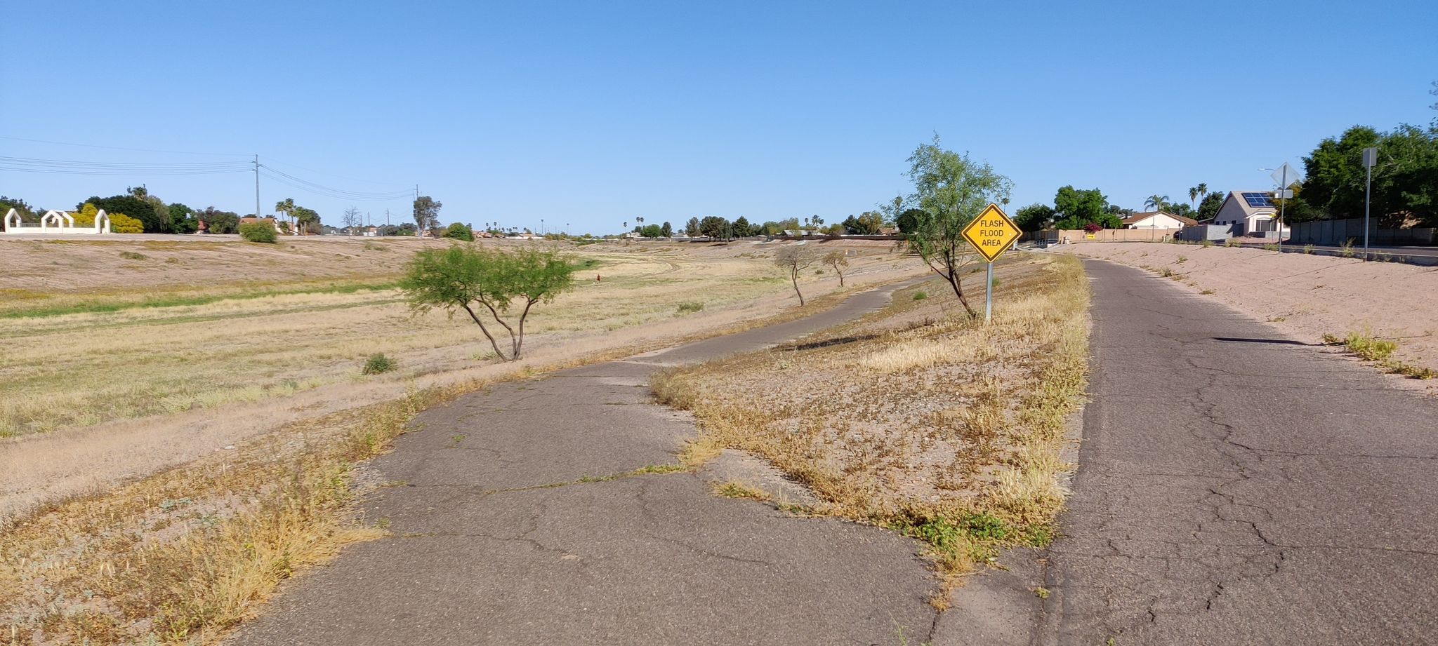 Paved path splitting through dry, grassy landscape under bright blue sky. - Arizona Diversion Trail