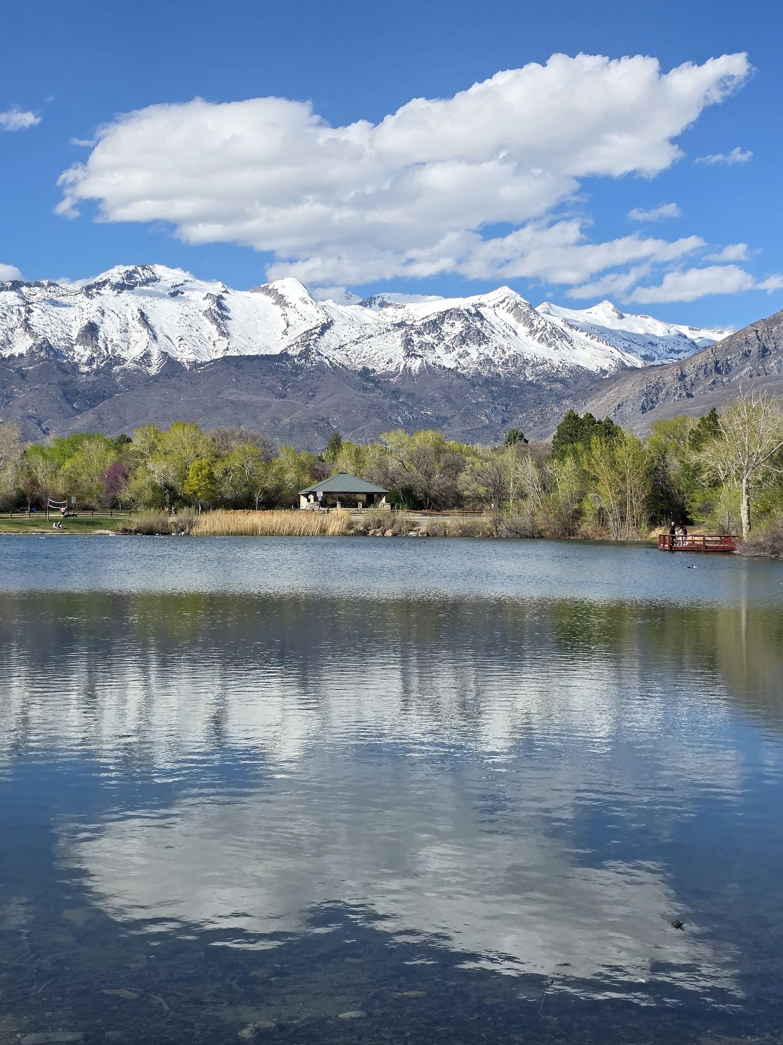 Calm lake reflecting sky and snow-capped mountains with a distant cabin. - Highland Glen Park Loop