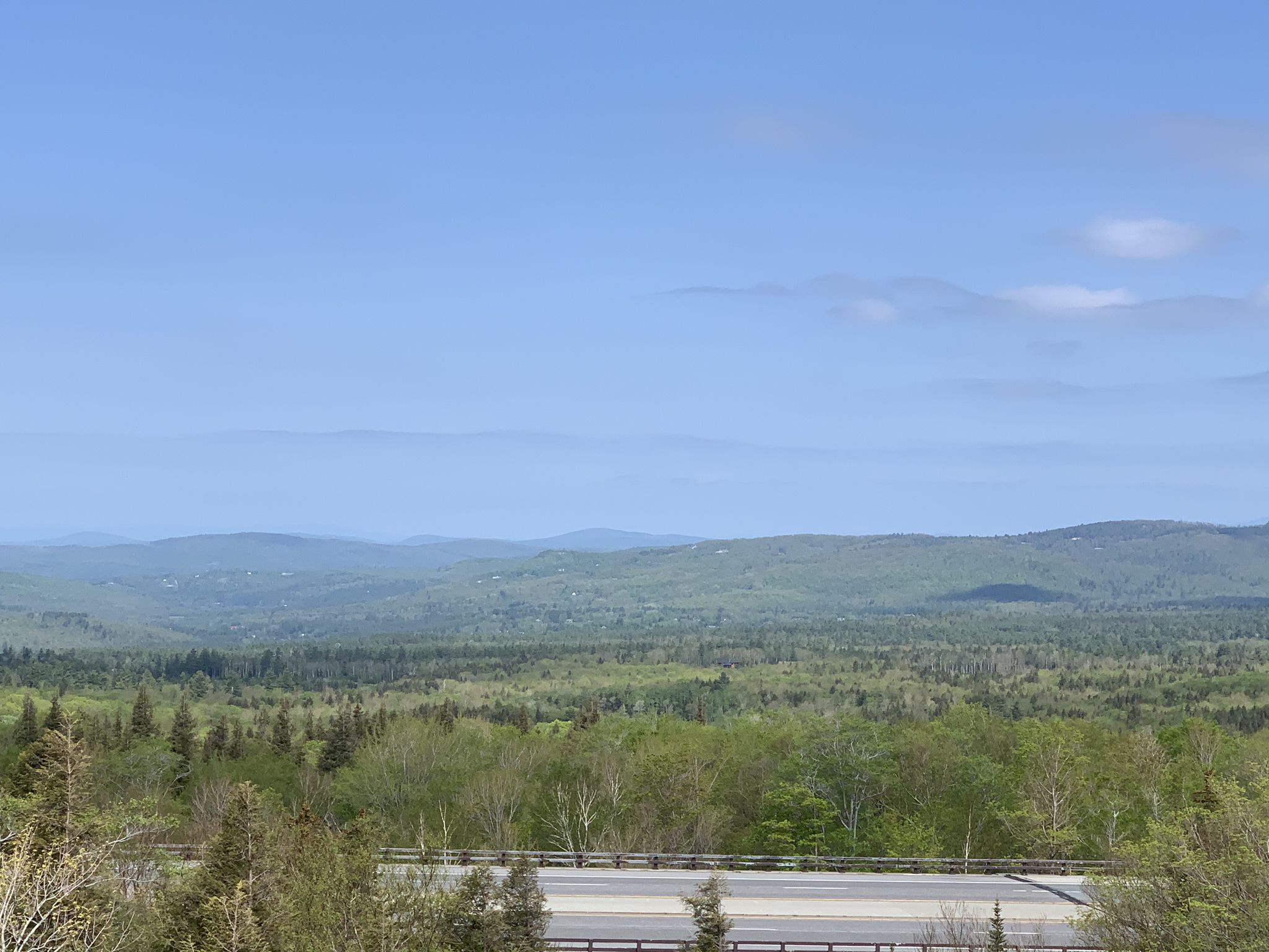 Expansive view of rolling forested hills under a bright blue sky. - Franconia Notch Bike Path loop