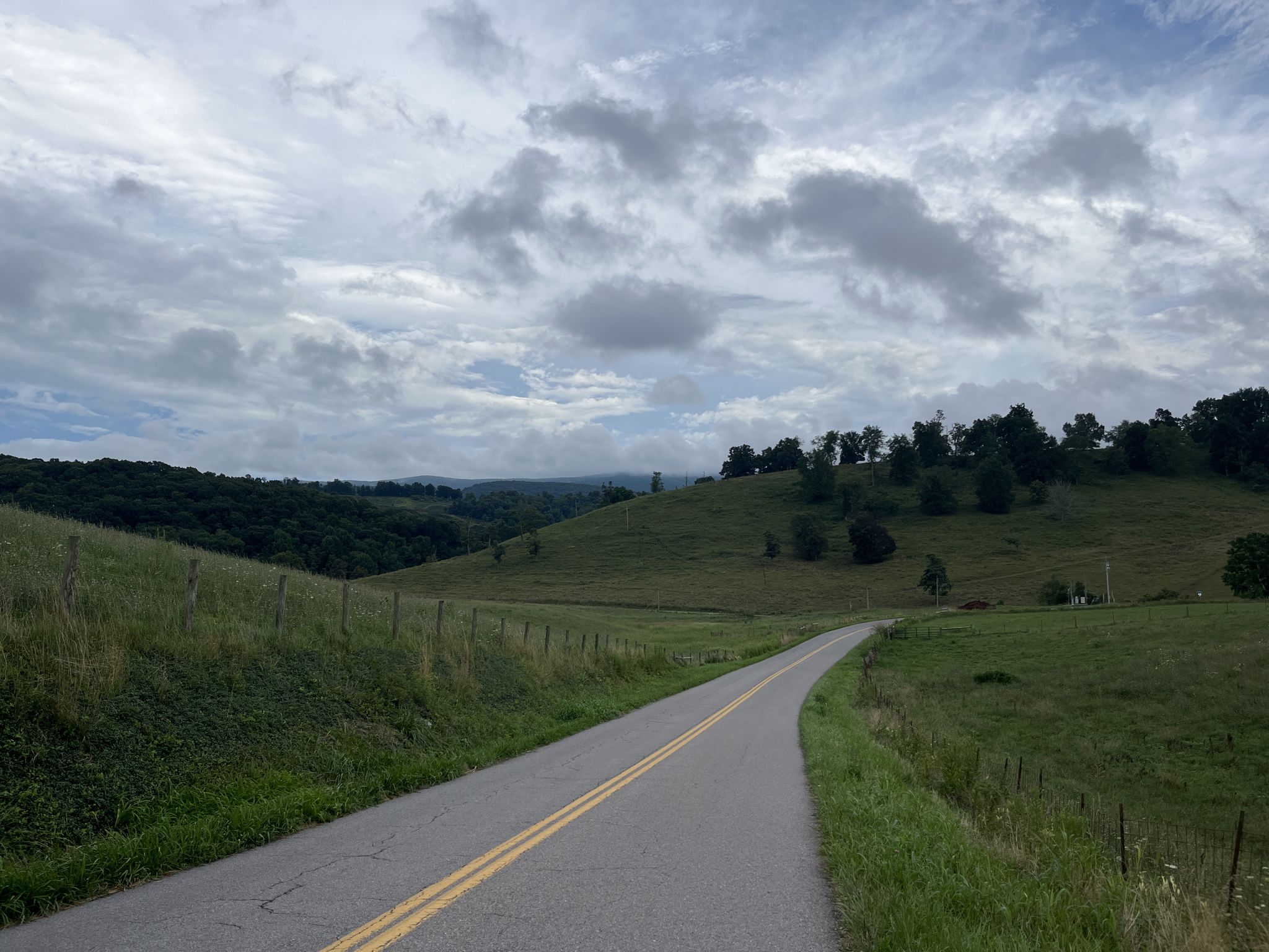 A winding road through rolling green hills under a cloudy sky. - Little Dry Run Wilderness loop