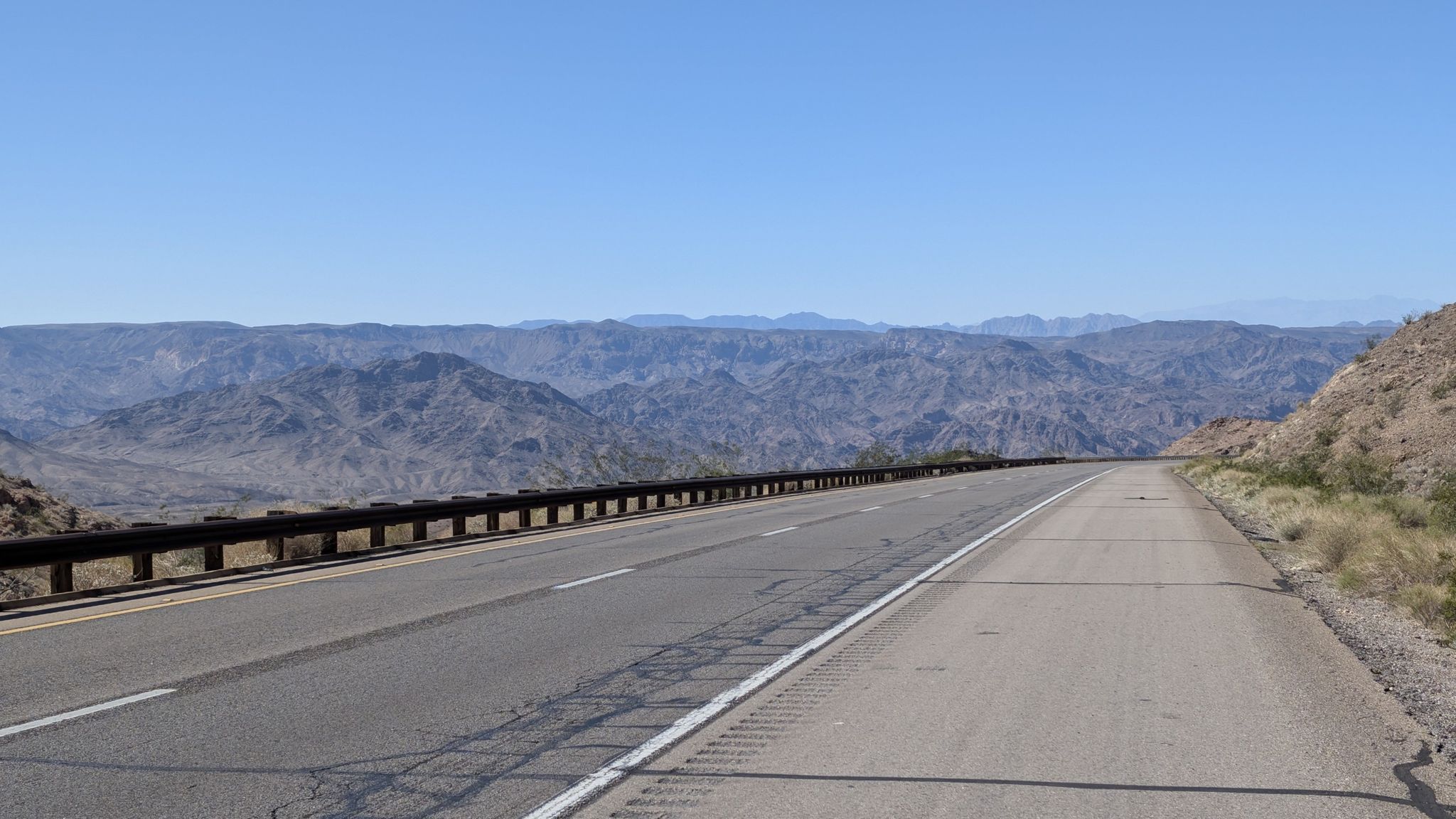 Desert highway with a guardrail, mountains, and clear blue sky. - Willow Beach to Temple Bar Marina