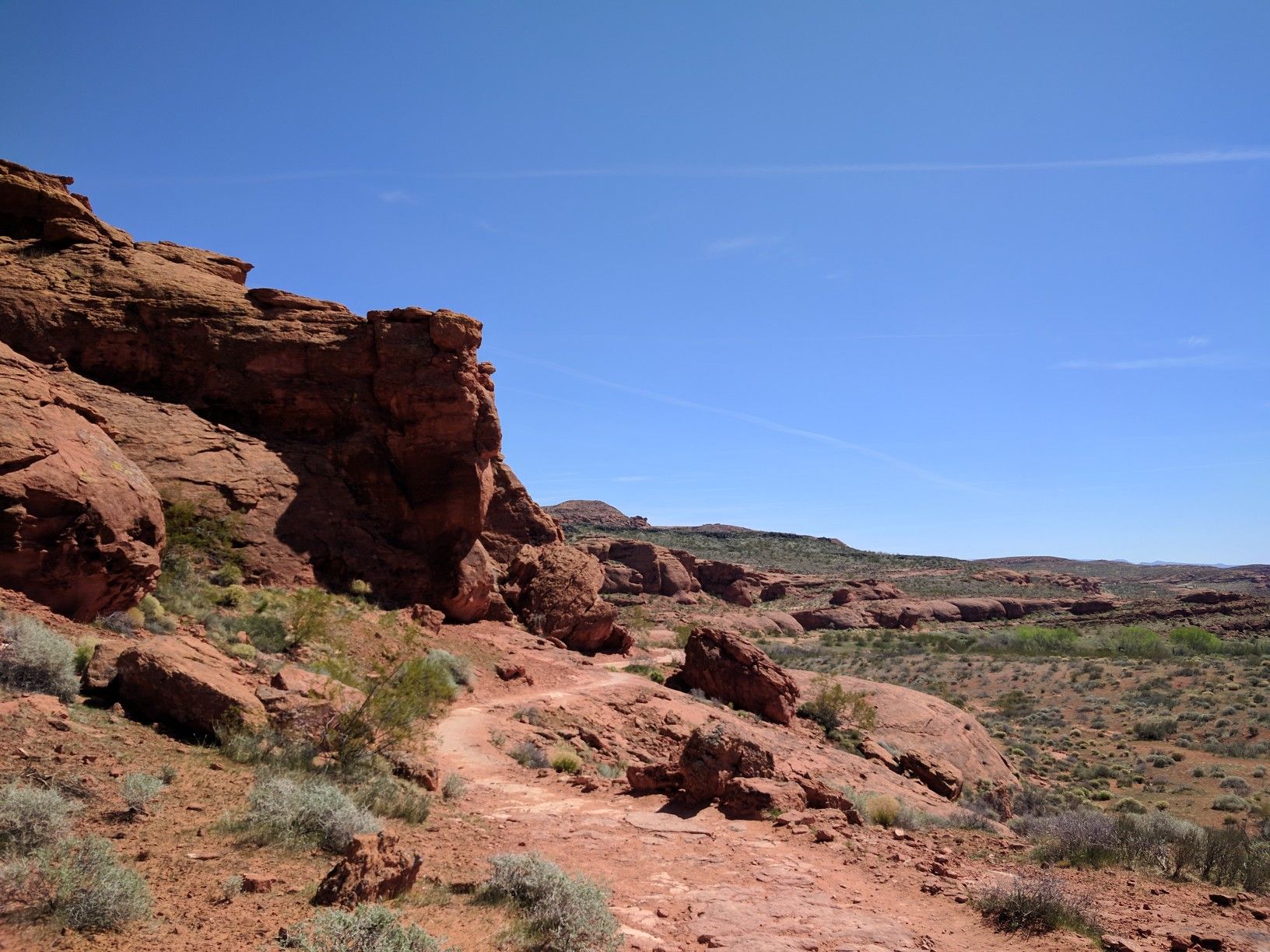 Winding red dirt path next to red rock cliffs in a desert. - Turtle Wall and Paradise Rim Loop