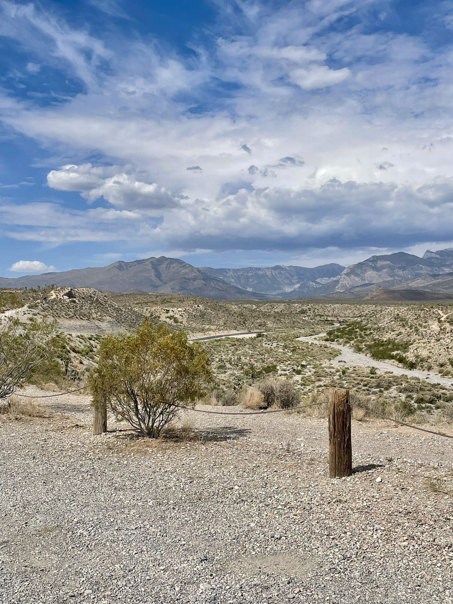 Arid desert landscape with distant mountains under a bright, cloudy sky. - Twilight Loop Trail