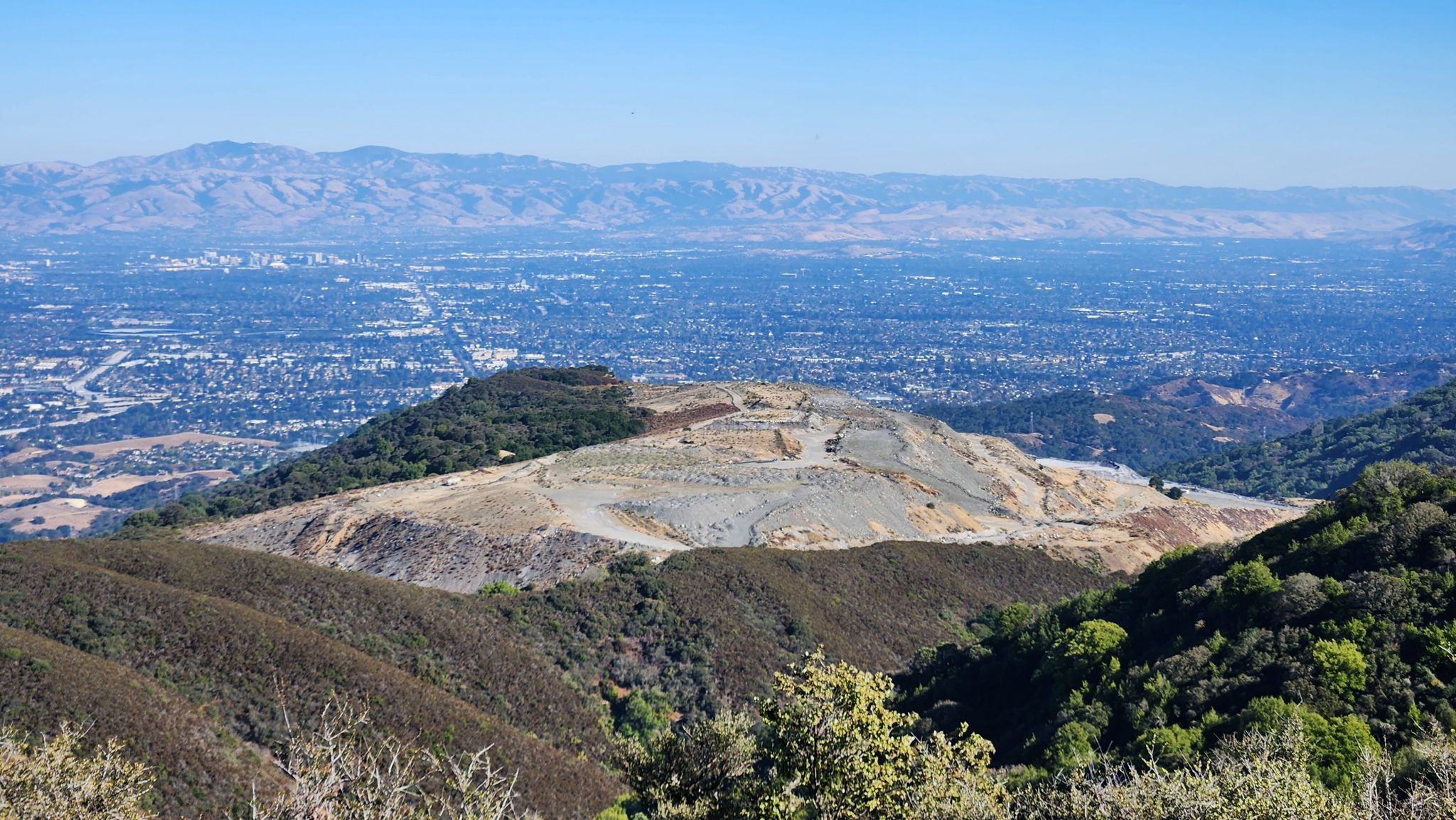 Panoramic view of a city and mountains, with a large excavated hill. Bright day. - Rancho San Antonio County Park – Black Mountain loop from Rancho San Antonio County Park