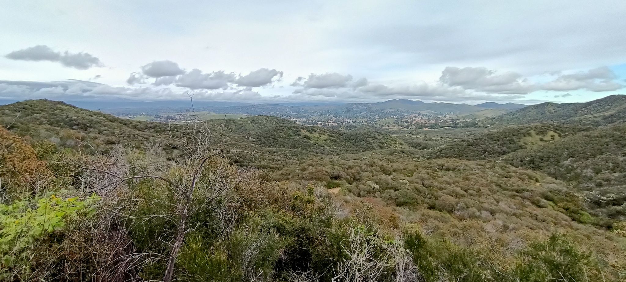 Panoramic view of green, rolling hills and a distant town under cloudy sky. - Space Mountain and Rosewood Trail Loop
