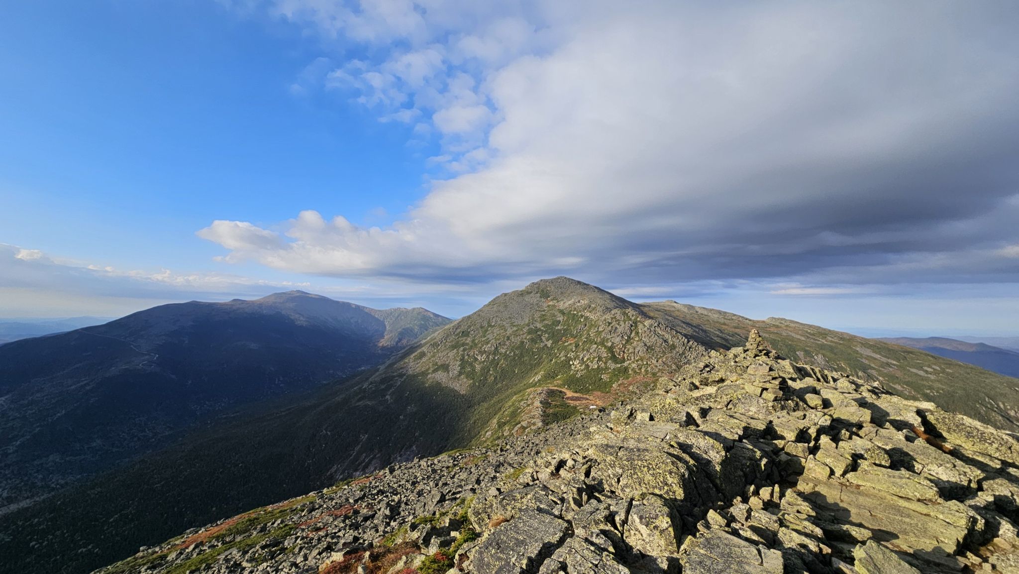 Rocky mountain ridge under a partly cloudy sky with distant peaks. - Valley Way Trail