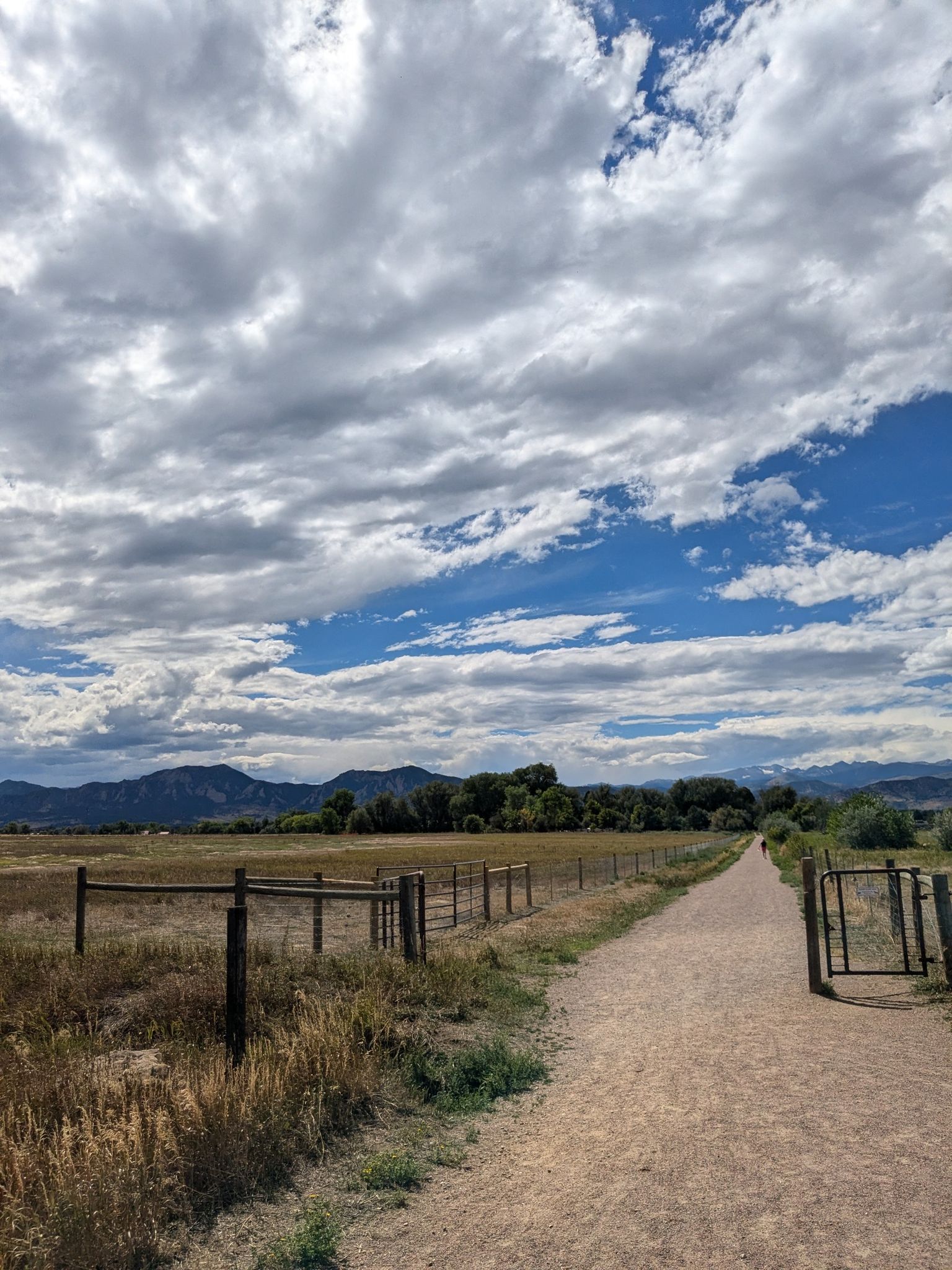 A long dirt path with a wooden fence, leading towards distant mountains. - East Boulder–Teller Farm Trail loop from Teller Farms South Trailhead