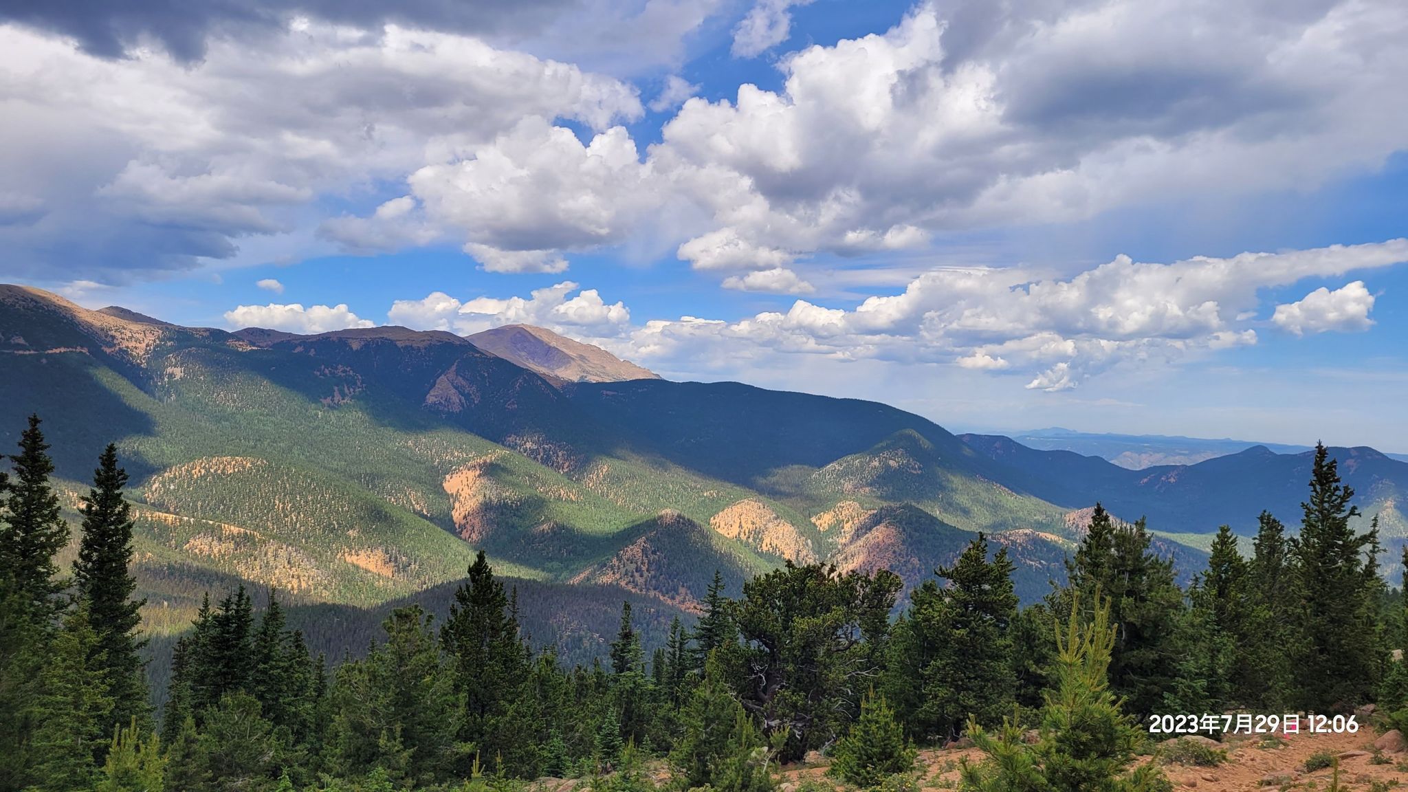 Mountain range with green forests under a blue sky with white clouds. - Mount Rosa Trail