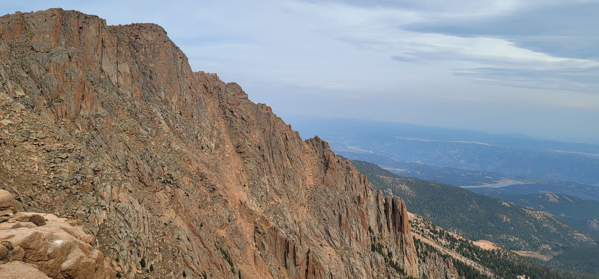 Steep, rugged mountain cliff face overlooking a vast valley. - Pikes Peak Highway: Cascade to the Summit of Pikes Peak