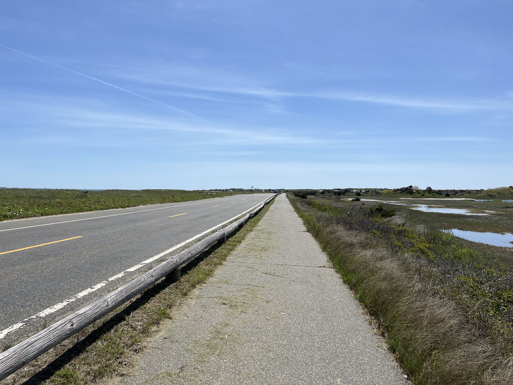 Paved road and gravel path alongside a marshy landscape. - Historic Edgartown – Joseph Sylvia State Beach loop from Edgartown