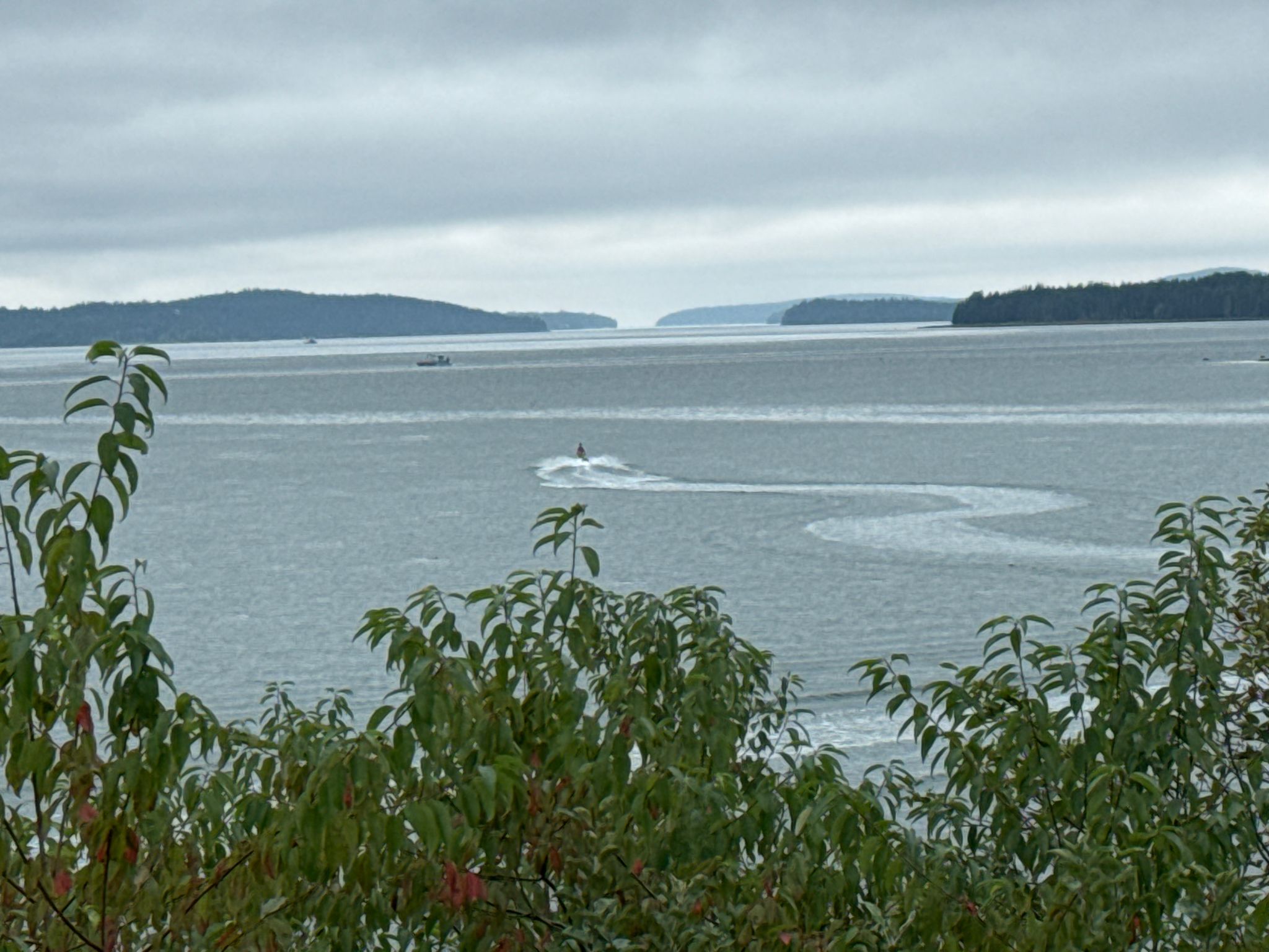 Wide water view with distant islands and a boat creating wakes. - Ellsworth to Bar Harbor loop