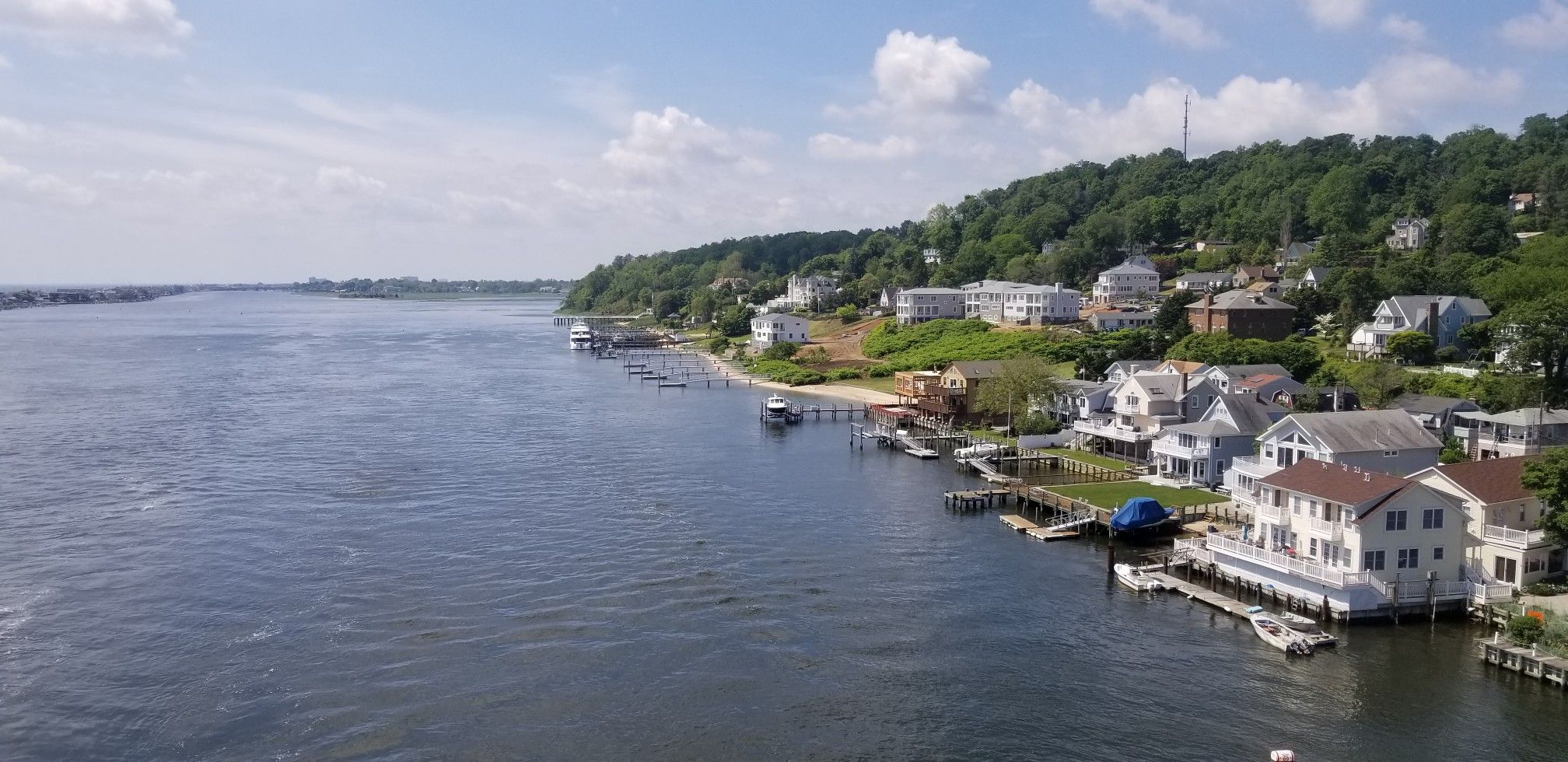 Wide river with houses on a green, sunny hillside and docked boats. - Shrewsbury River Bridge – Highlands Beach loop from Highlands