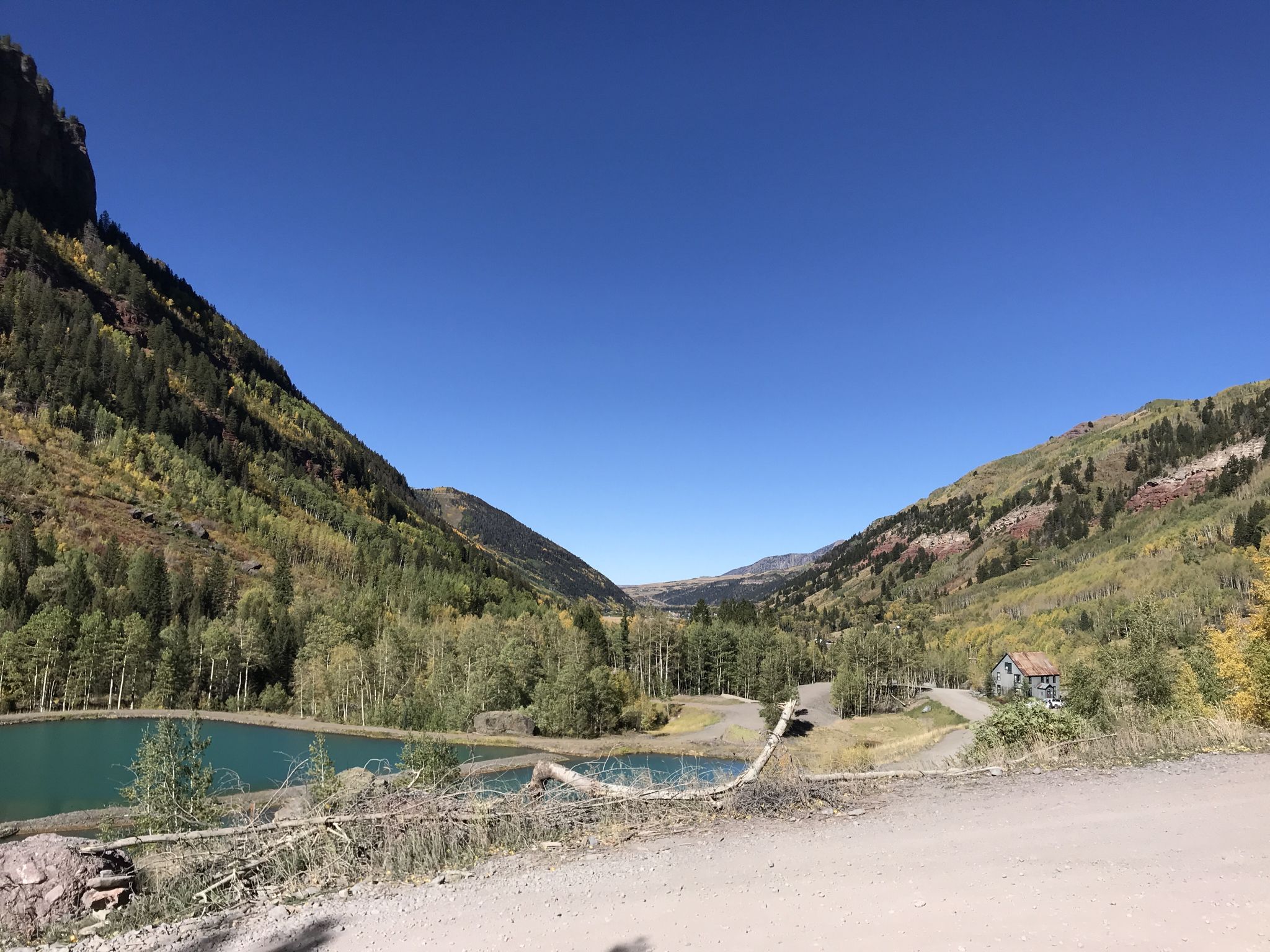Mountain valley with two turquoise ponds and a small building under clear skies. - Bridal Veil Falls, Black Bear Pass Loop