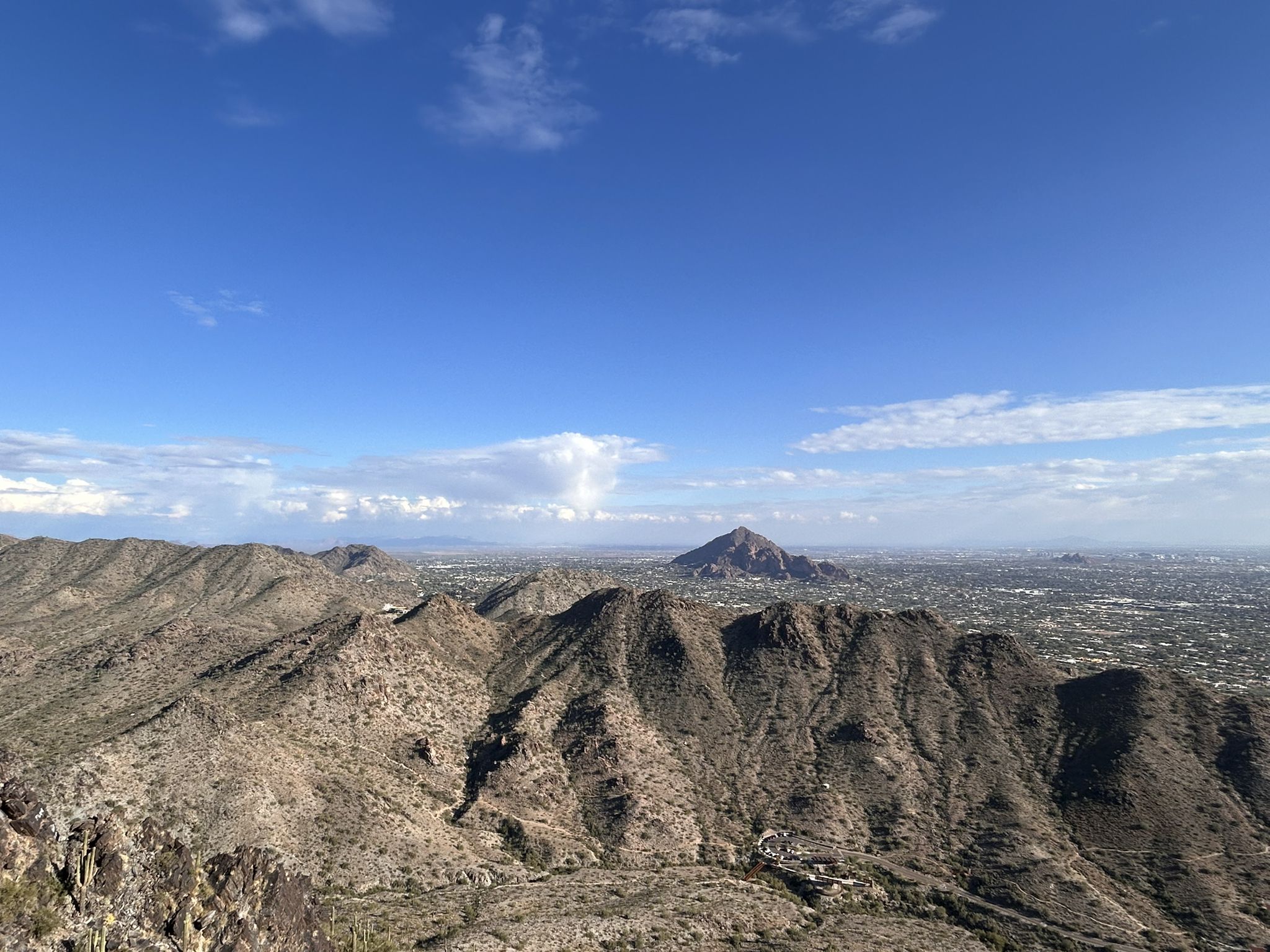 Wide desert mountain landscape under a blue sky with distant city. - Piestewa Peak Summit Trail