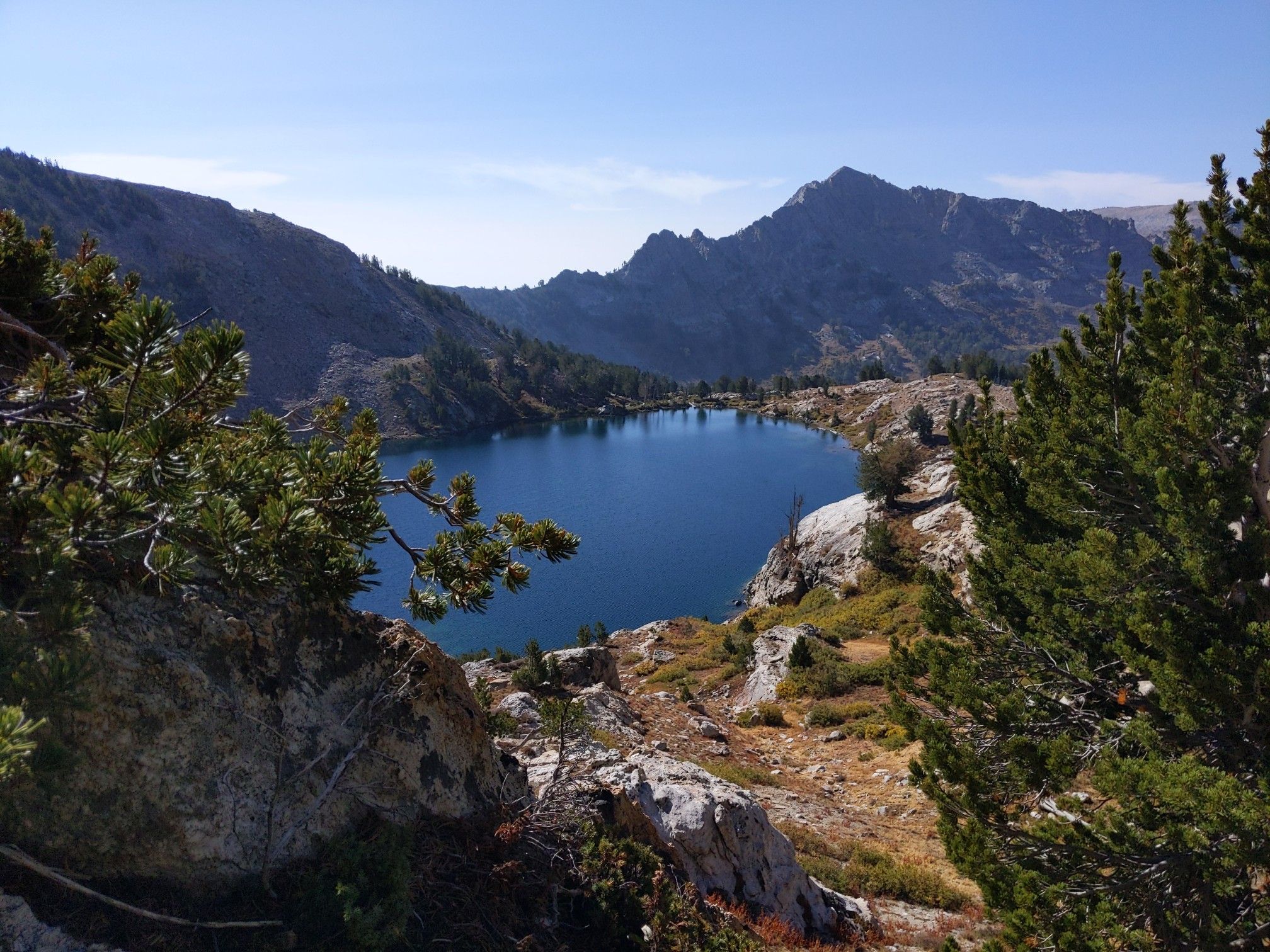 Deep blue mountain lake surrounded by rocky shores and distant peaks on a clear day. - Castle Lake Loop