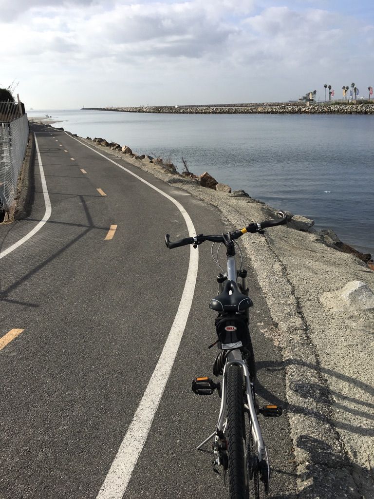 Bicycle on a paved path curving alongside a body of water, bright day. - San Gabriel River Trail