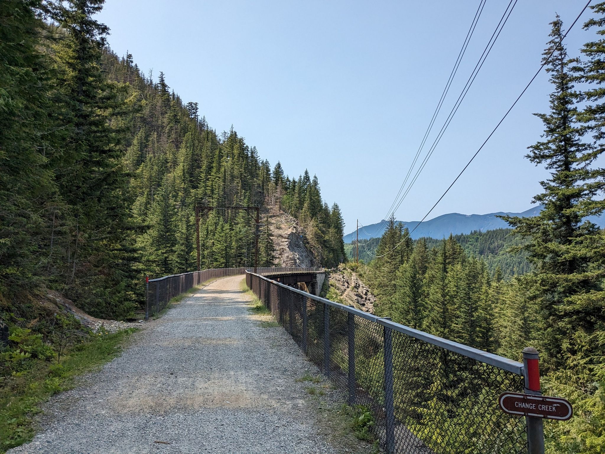 Gravel path on a bridge through a sunny pine forest with distant mountains. - Change Creek Trestle – Hall Creek Trestle loop from Olallie State Park South Fork Fishing Access