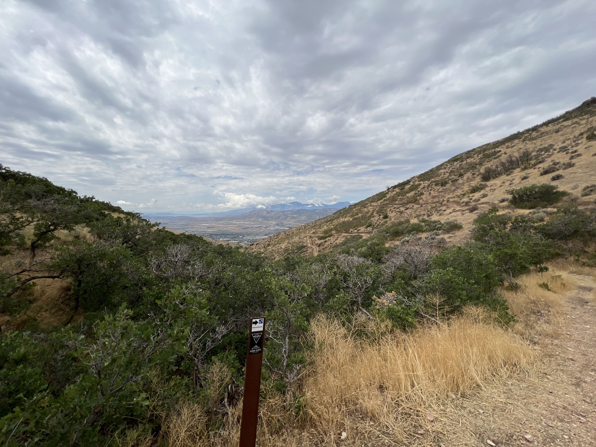 Overcast view of a valley between two hills with a trail marker. - Sensei and Lolo Loop Trail