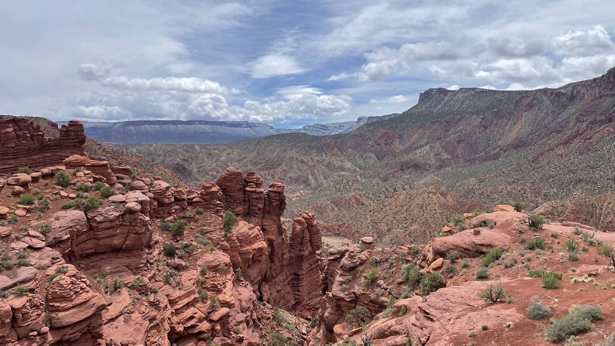 Expansive desert canyon landscape with red rock formations under a cloudy sky. - Fisher Towers Trail