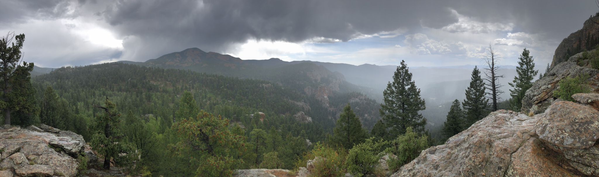 Panoramic view of a forested mountain landscape under a dramatic, stormy sky. - Lions Head via Scout Line and Bugling Elk Trail