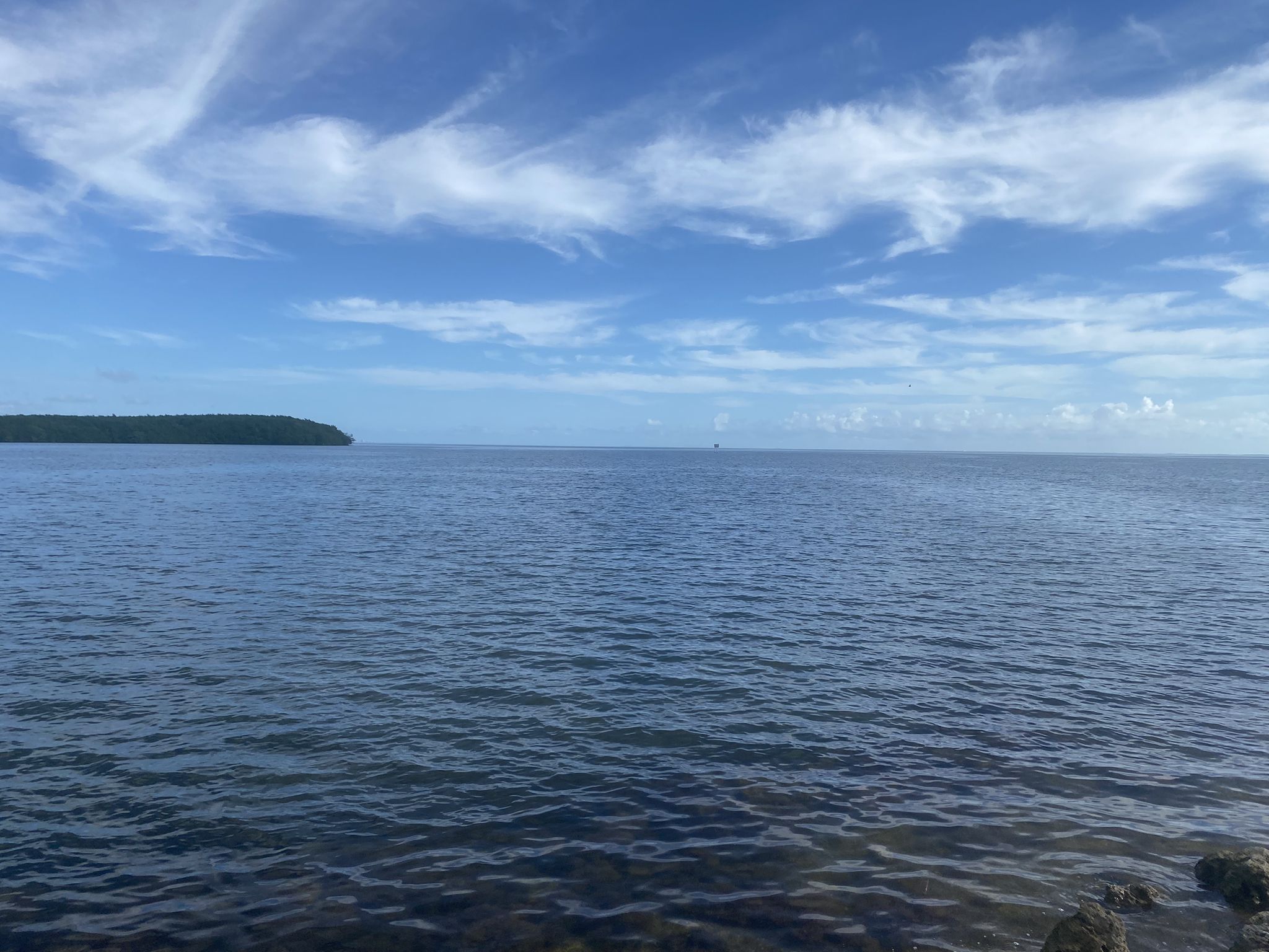 Vast blue water under a partly cloudy sky, with distant land. - Black Creek Trail