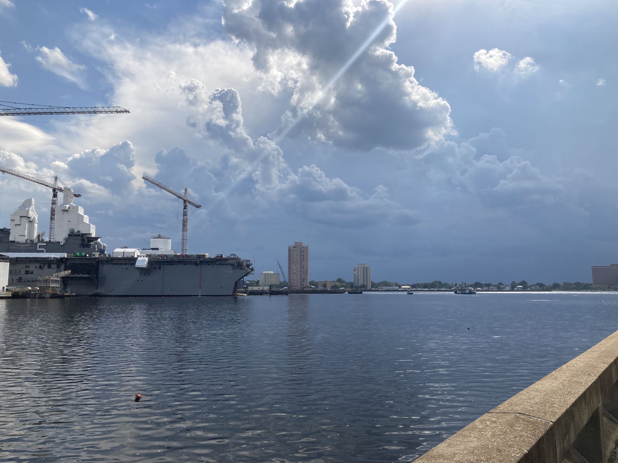 Large gray ship and cranes in a harbor under a dramatic cloudy sky. - Elizabeth River Trail