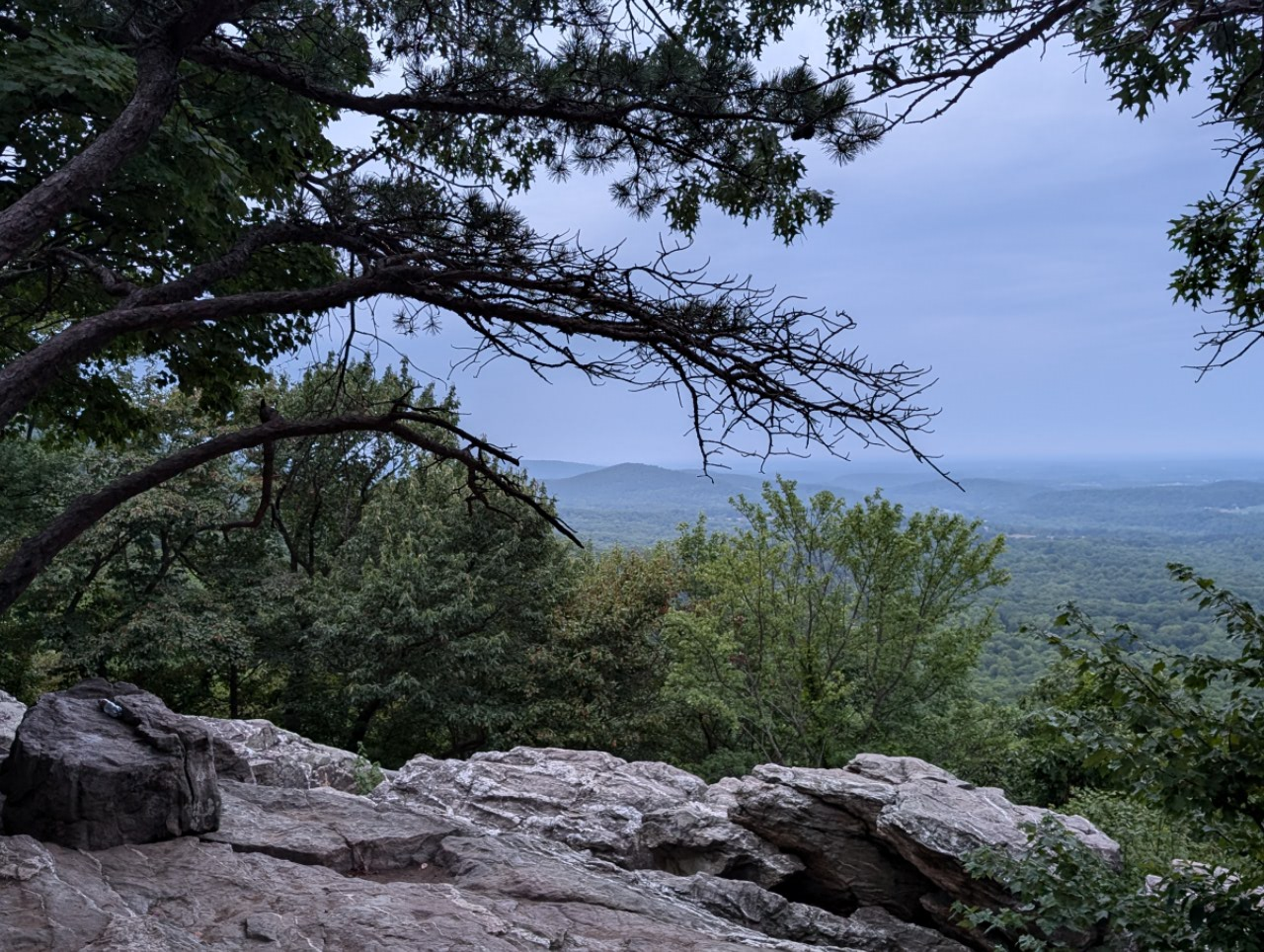 Overcast view from a rocky overlook showing distant forested hills. - Bear's Den Park Trail