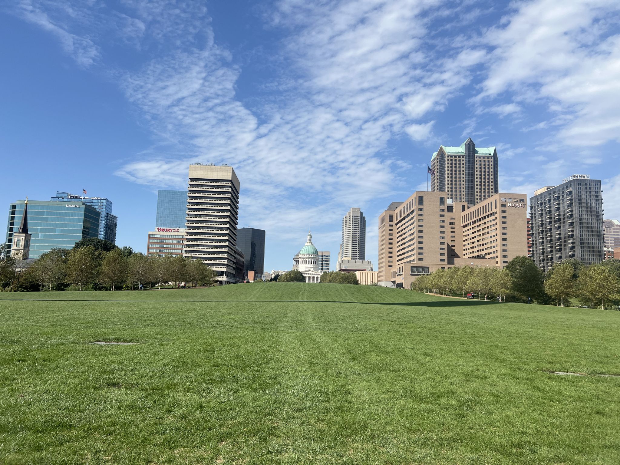 Expansive green lawn with a city skyline and domed building in the distance. - St. Louis Riverfront Trail