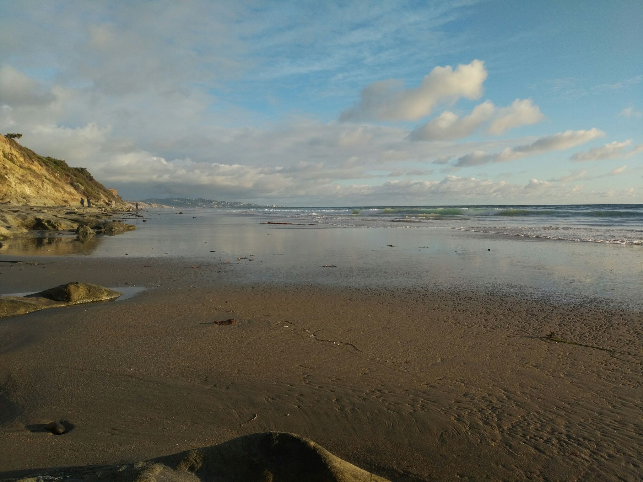 Sandy beach with calm ocean waves and steep cliffs under a cloudy sky. - Del Mar Beach & Seagrove Park from Solana Beach