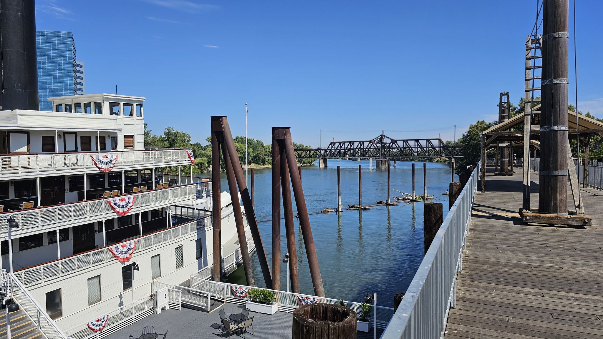 Large white paddleboat docked by a river with a bridge in the background on a sunny day. - Old Sacramento and Capitol Promenade