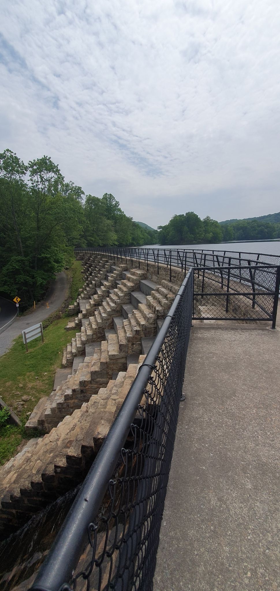 Concrete dam with steps and a fence next to a large body of water. - Bays Mountain Reservoir loop from Bays Mountain Park
