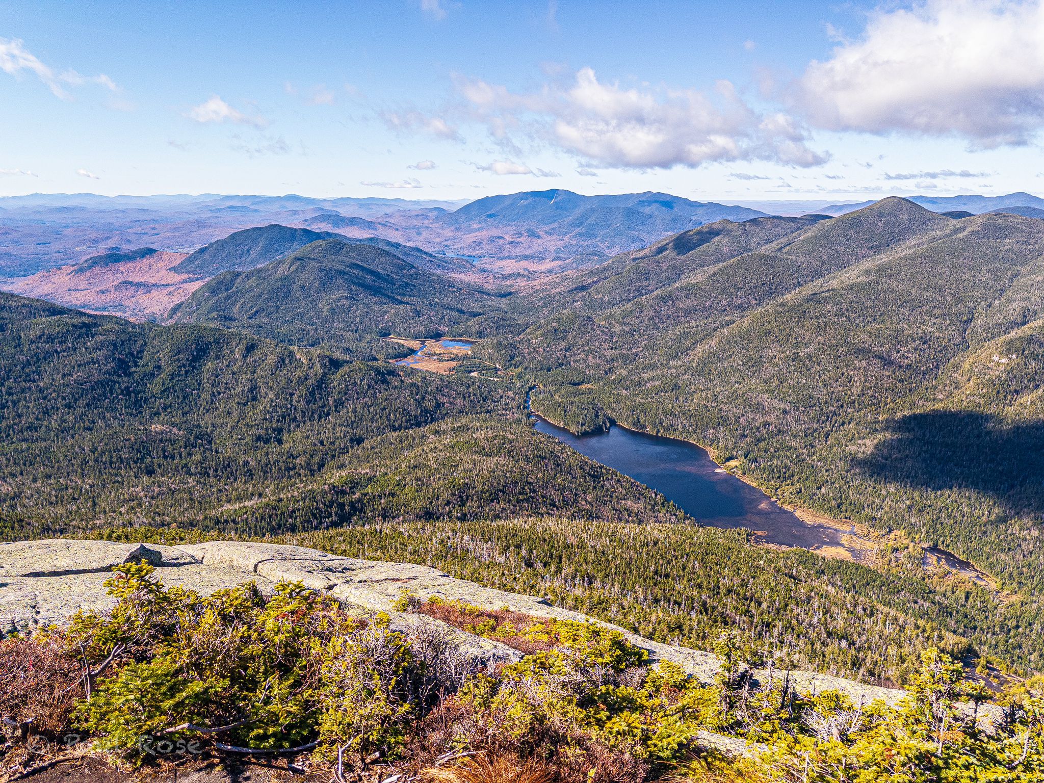 Panoramic view of forested mountains, a lake, and valleys under a blue sky. - Mount Skylight, Mount Marcy, and Gray Peak Loop Trail