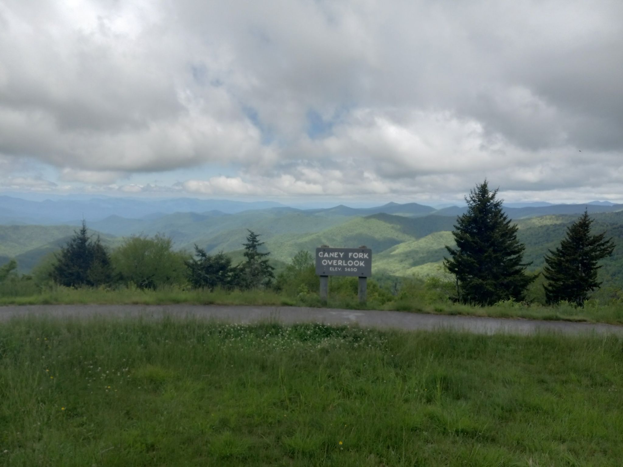 Overlook sign on a paved road with distant mountains under cloudy skies. - Richland Balsam loop