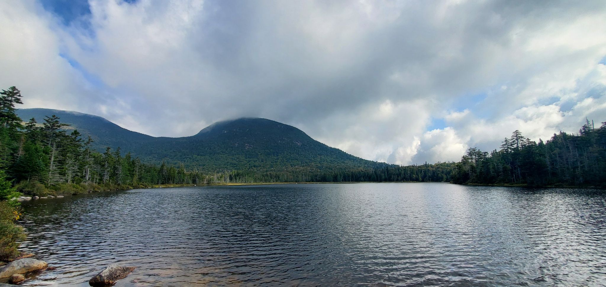 Wide lake with dark water, surrounded by forests and mountains under cloudy sky. - Kinsman Loop via AT and Cascade Brook Trail