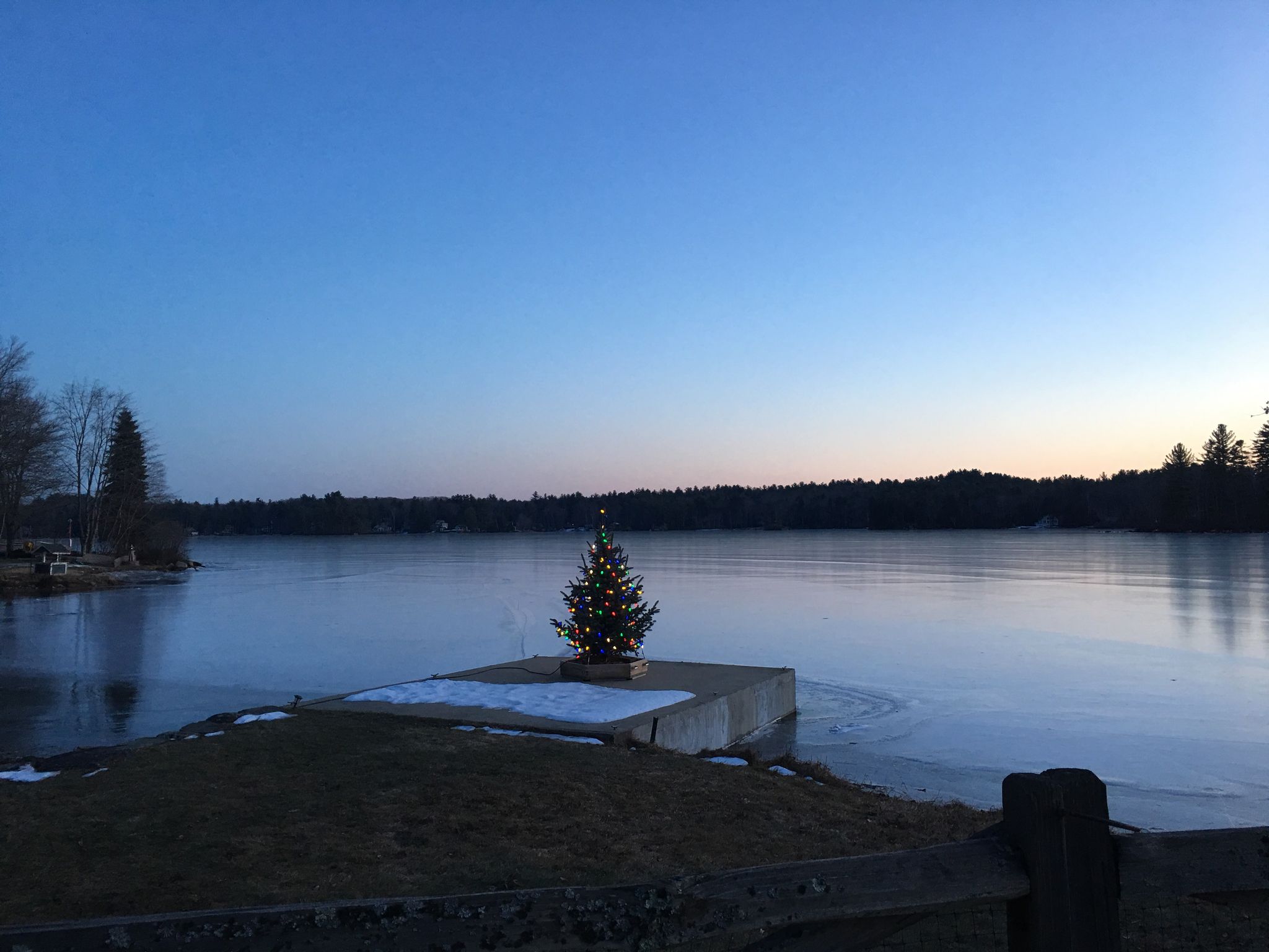 Lit Christmas tree on a dock over a partially frozen lake at dusk. - Swains Lake – Swains Lake loop from Newhall Conservation Land