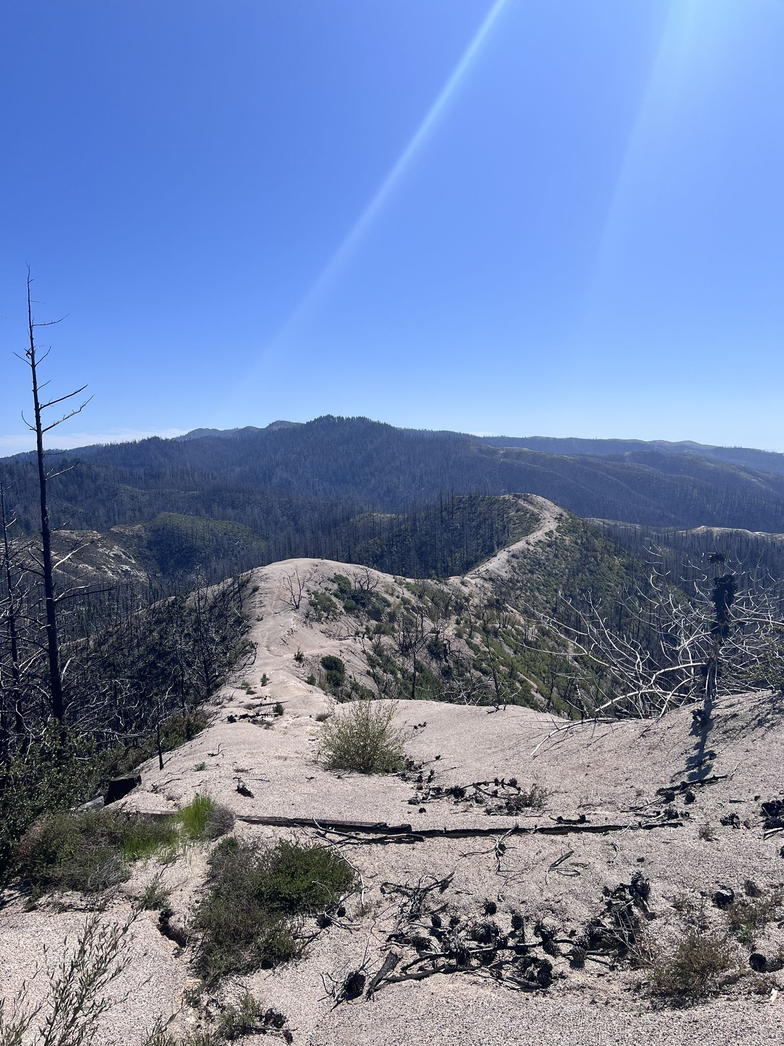 A sandy ridge overlooks distant mountains under a bright, clear sky. - Skyline To The Sea Mountain Bike