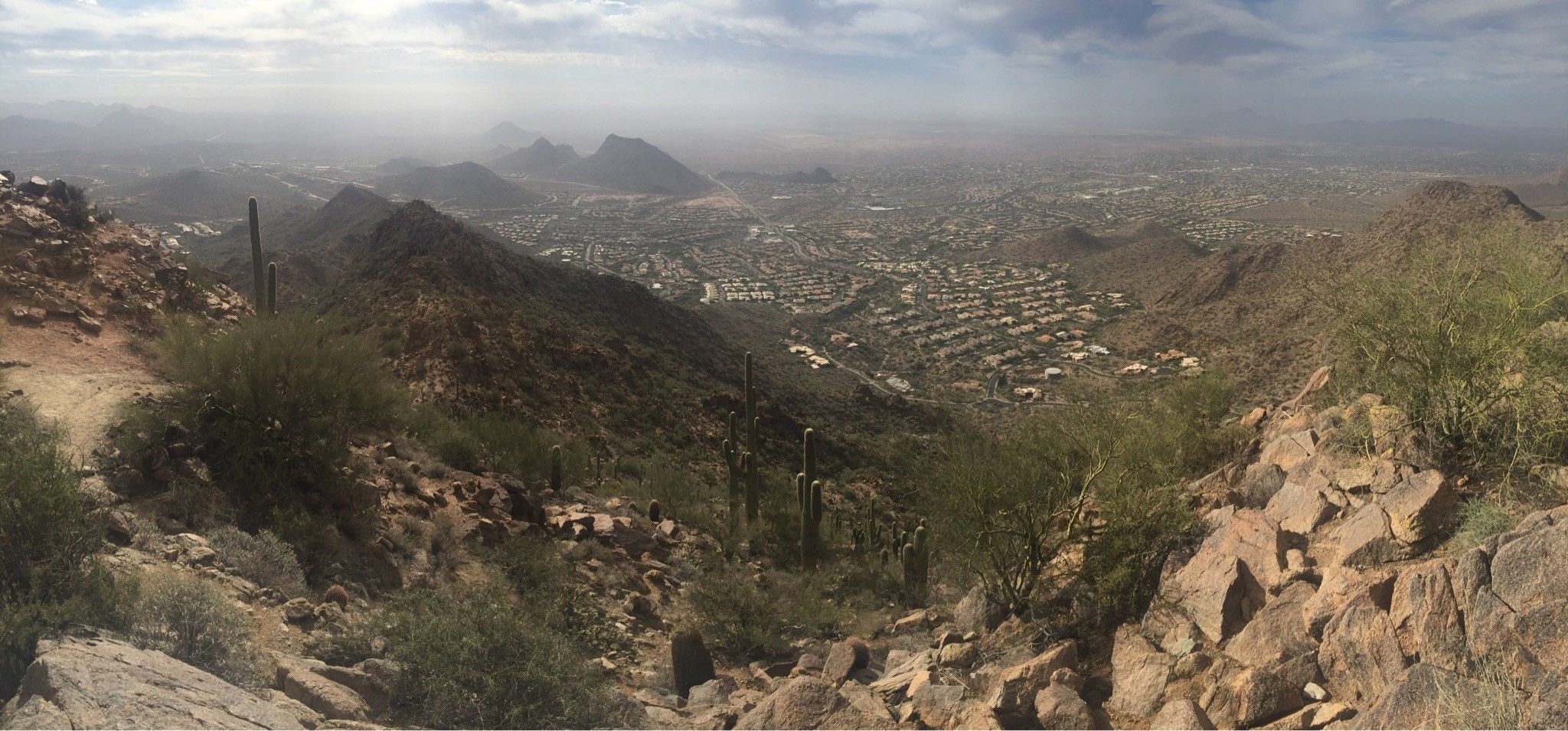 Panoramic view of a sprawling city nestled among desert mountains under a hazy sky. - Sunrise Peak via Sunrise Trail