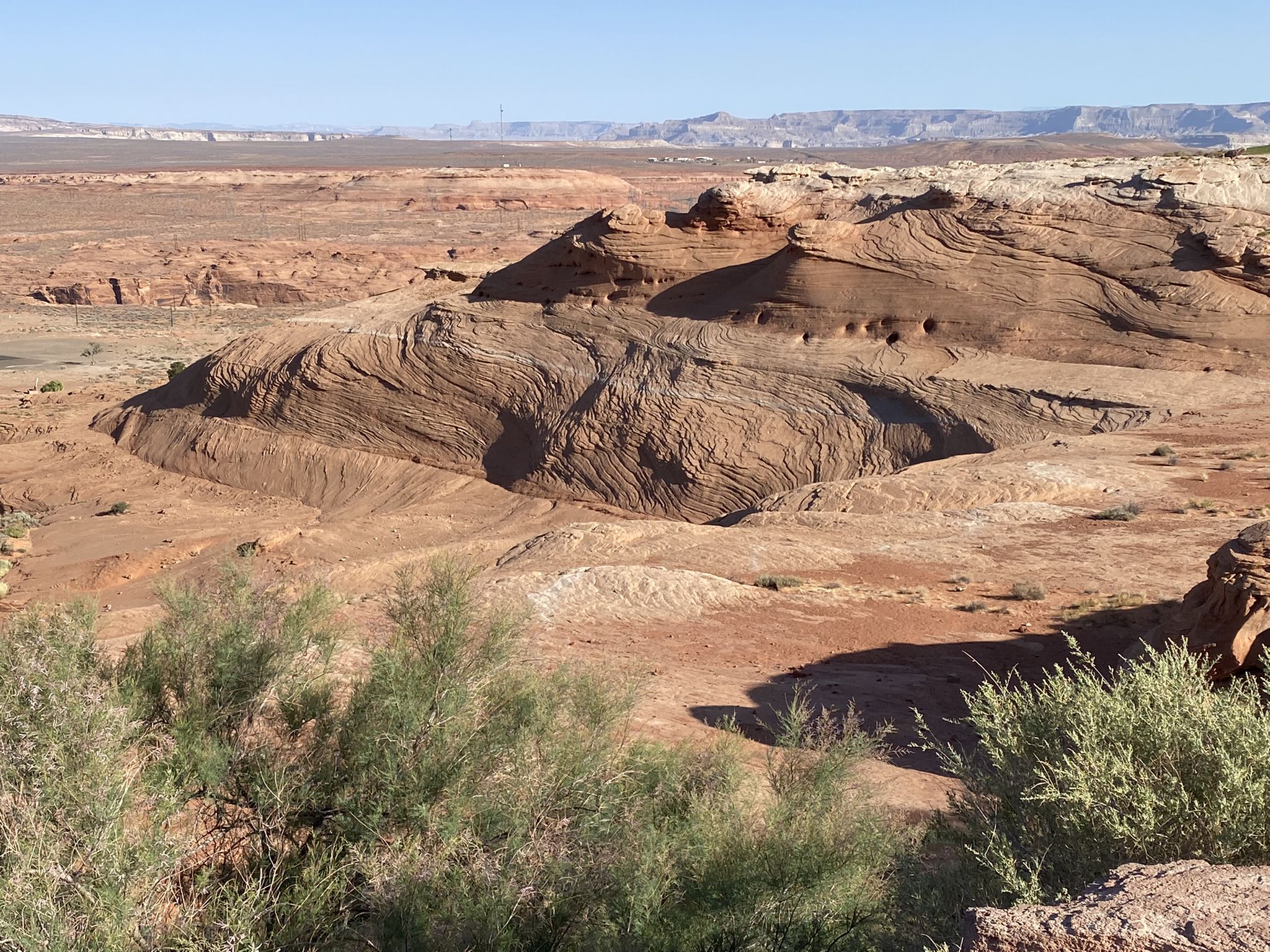 Intricate swirling red rock formations dominate an arid desert landscape. - Glen Canyon Dam Viewpoint – Glen Canyon Dam Overlook loop from Page