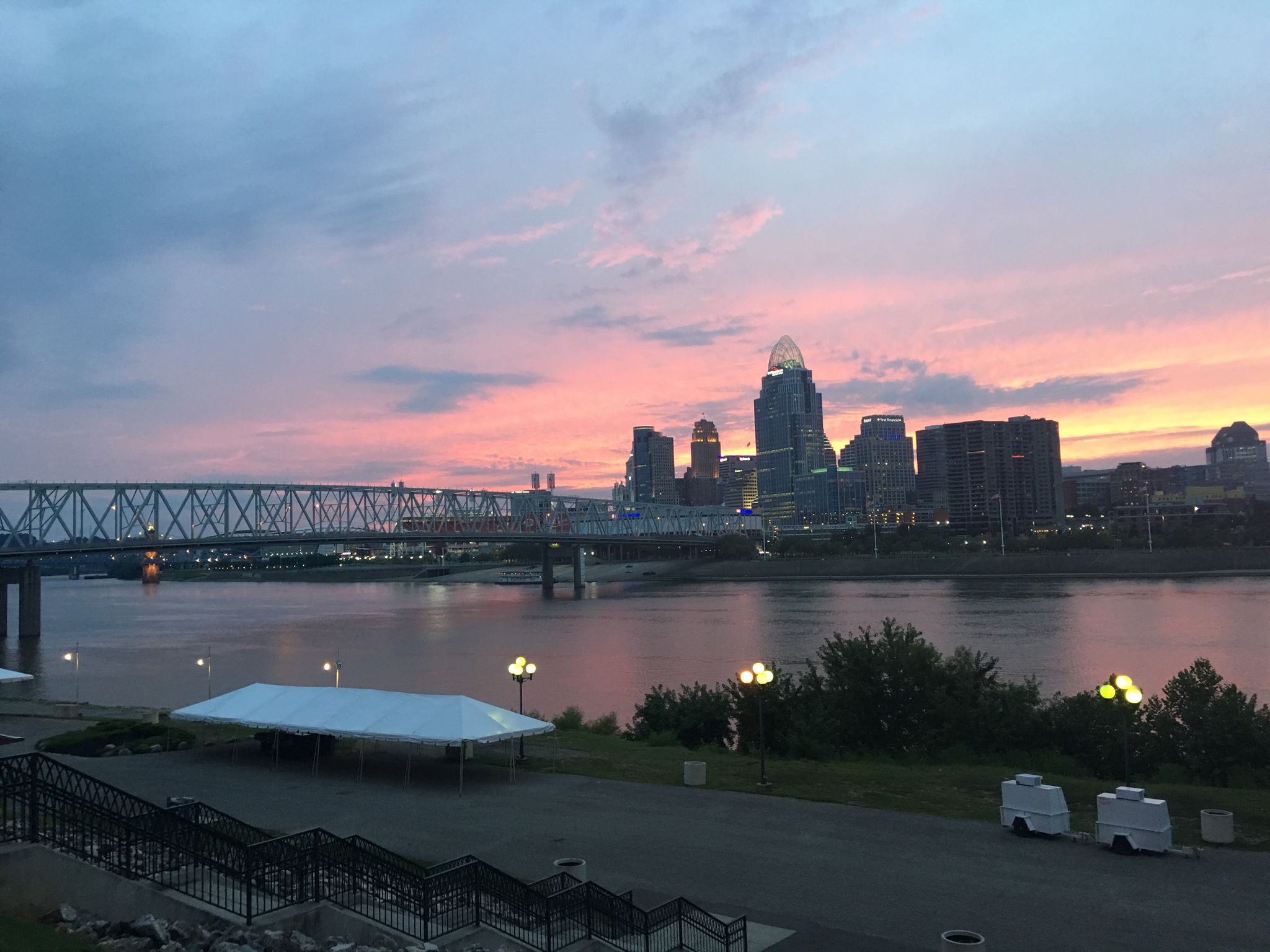City skyline and river at sunset, with a park area in the foreground. - Purple People Bridge loop from Newport
