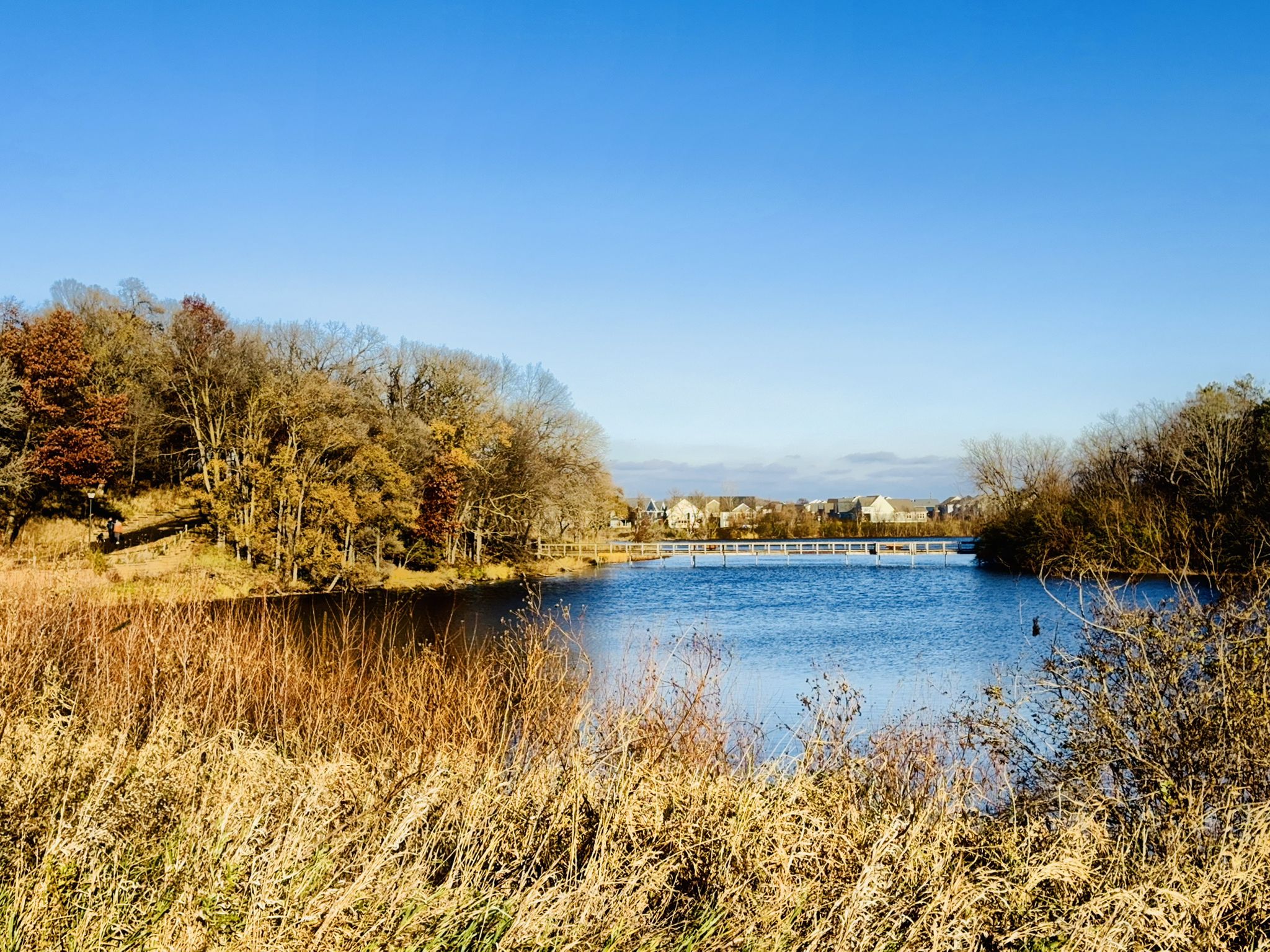 Bright sunny day over a lake with autumn trees and a distant bridge. - Cobblestone Lake and East Lake loop