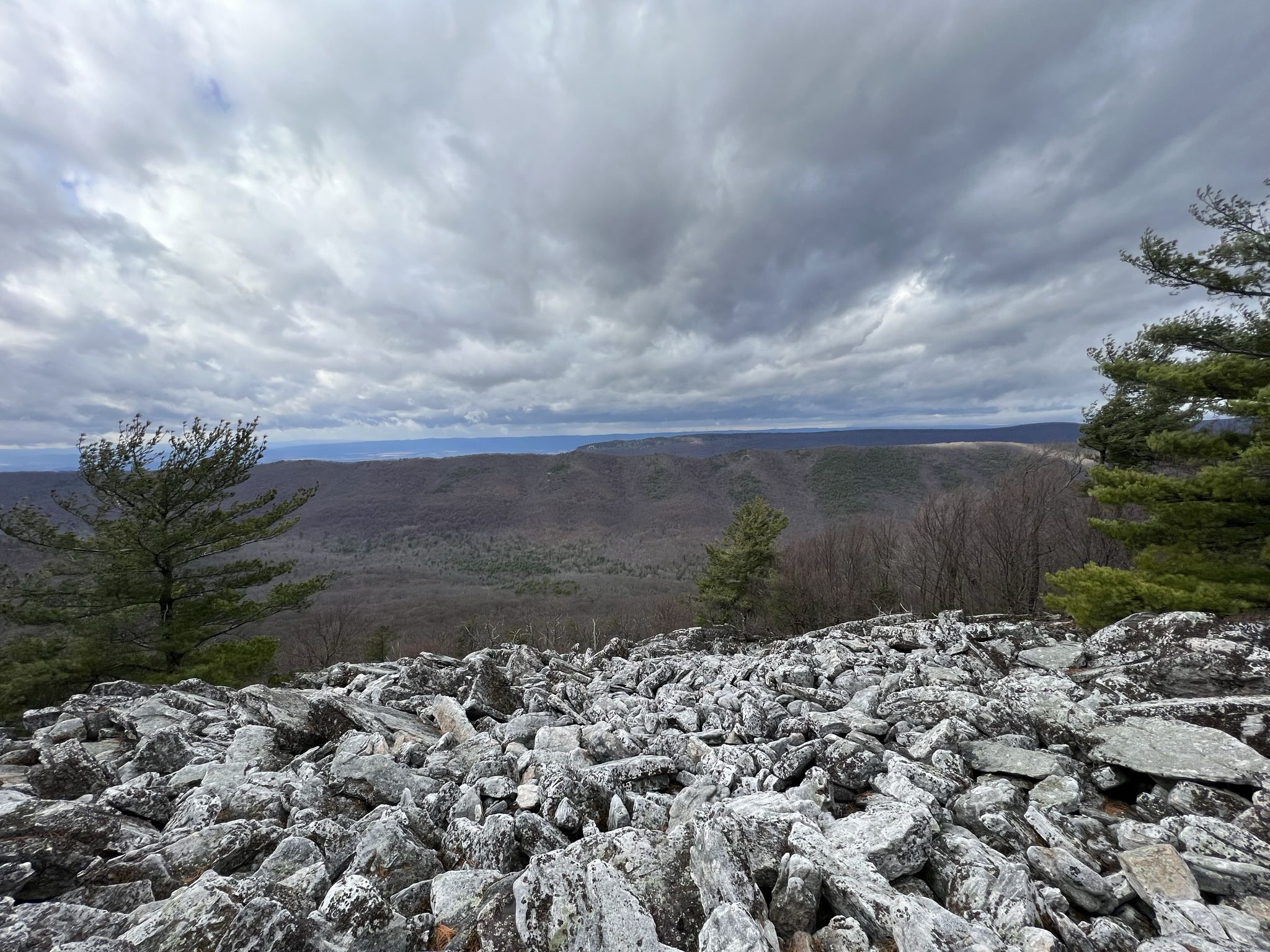 Rocky mountain overlook under a cloudy sky, with distant forested hills. - Hiking loop from Peach Orchard Gap Parking