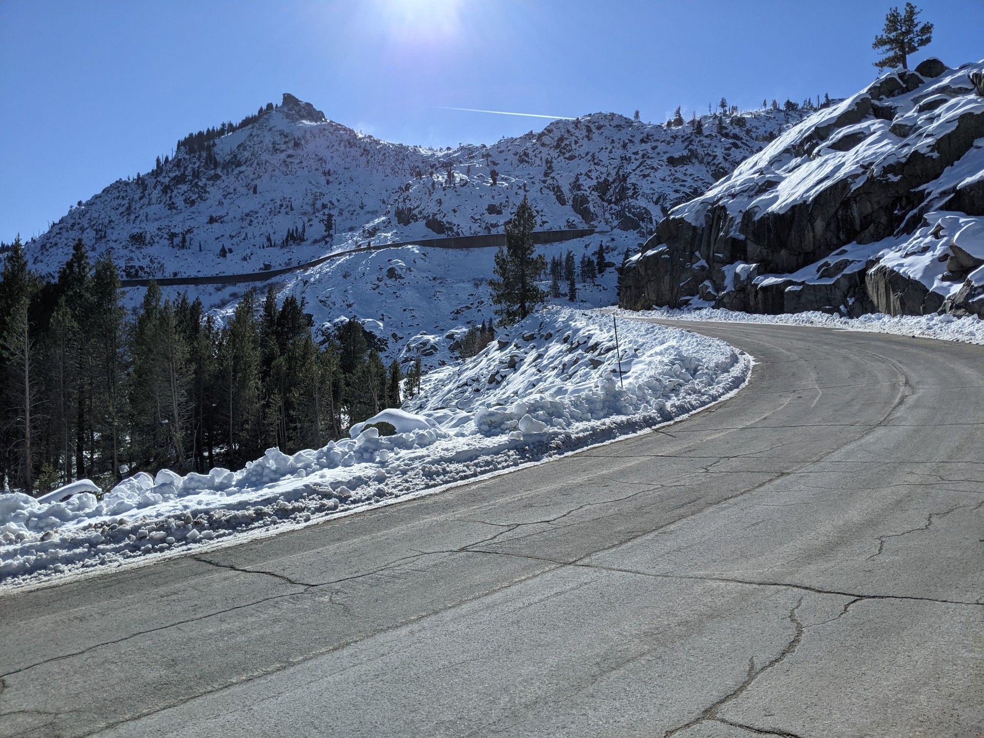 Winding road through snowy mountains and pine trees on a bright, sunny day. - Tahoe-Pyramid Bikeway and Donner Pass Loop