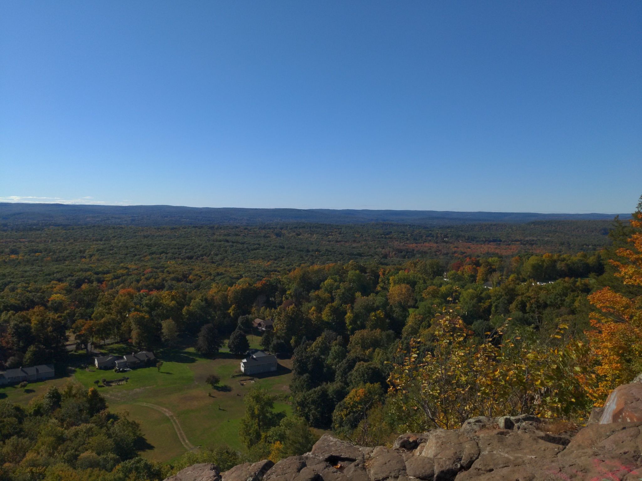 Expansive forest landscape with distant houses under a clear blue sky. - Peak Mountain Viewpoint loop from East Granby